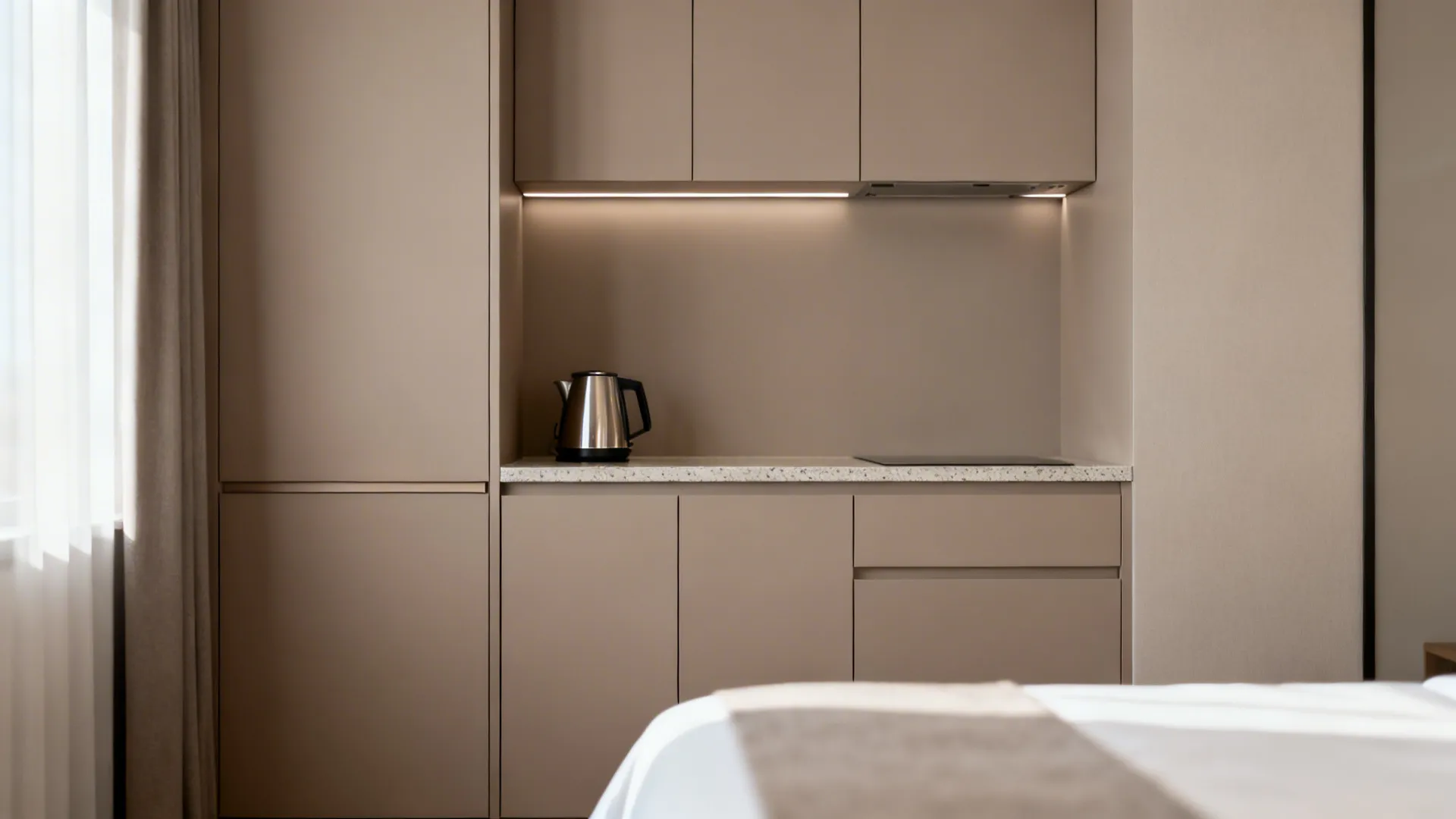 Compact hotel kitchenette with slab cabinets and hidden pulls for a clean, minimalist look.