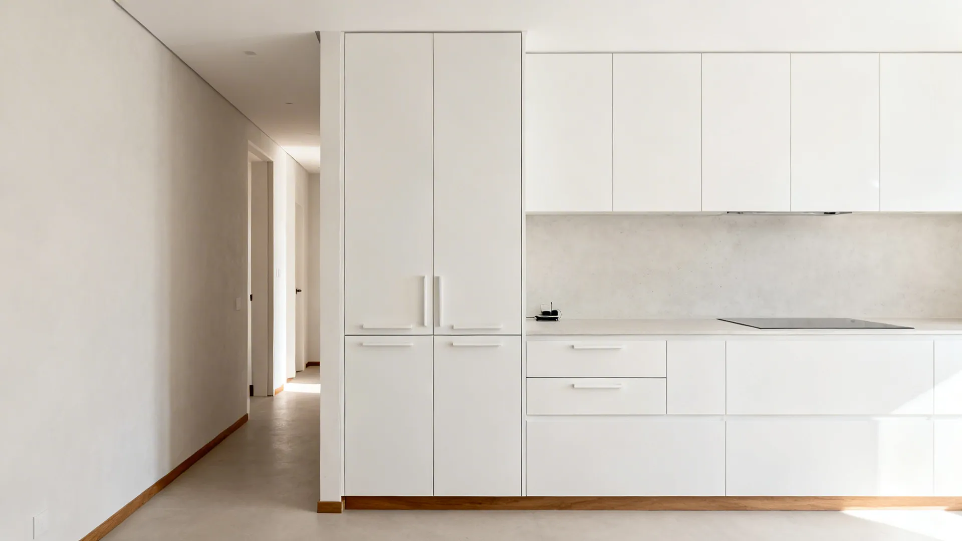 Modern white kitchen cabinets with wood trim beside a long hallway with white interior walls