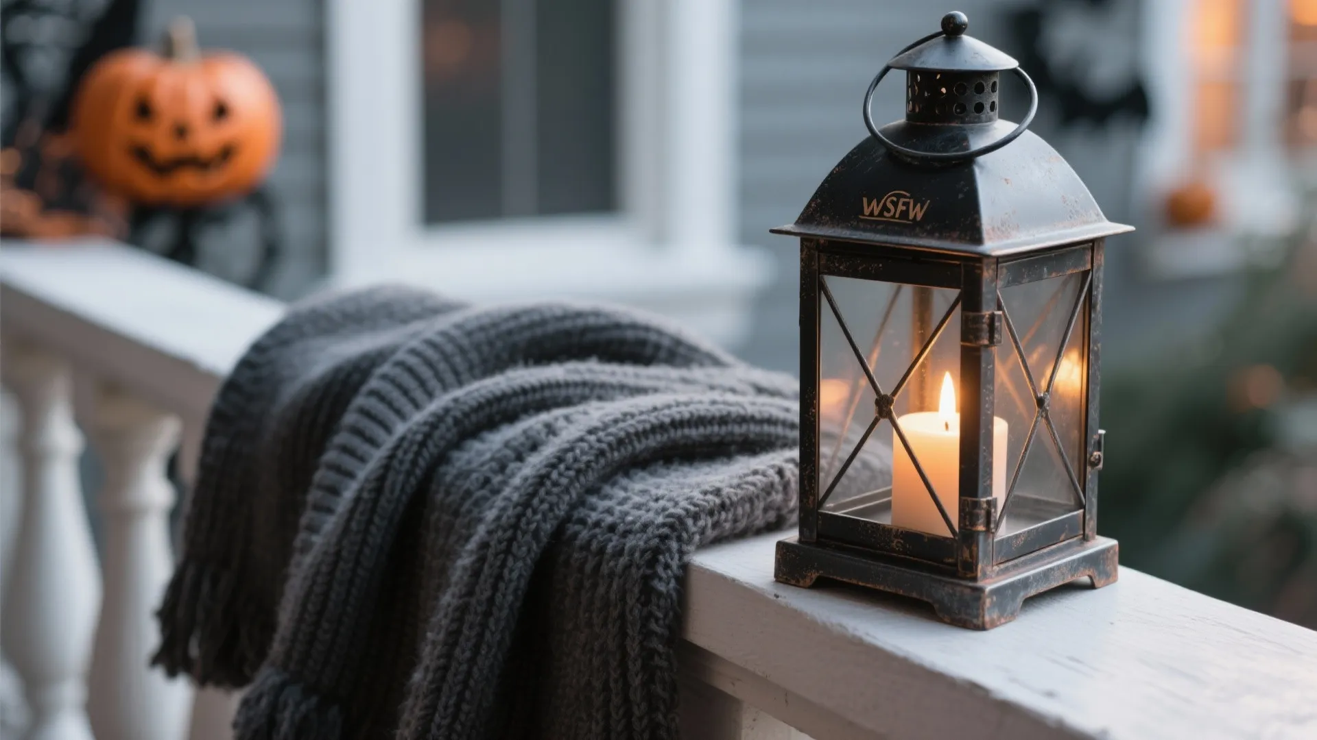 Macro of ribbed knit textile beside a matte black lantern with warm candle glow.