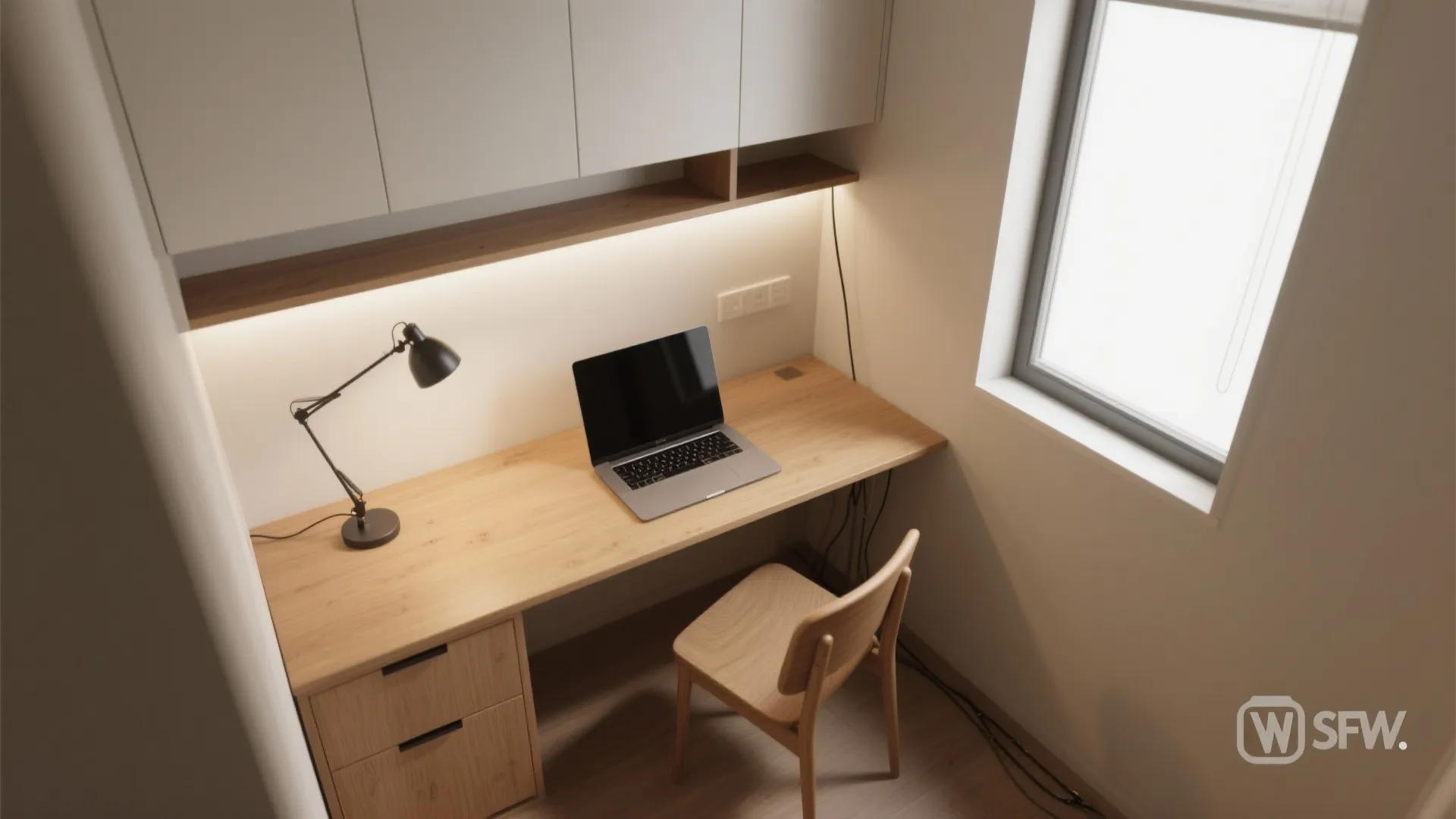 Small home office with wooden desk, laptop, black desk lamp, wooden chair, and white cabinets
