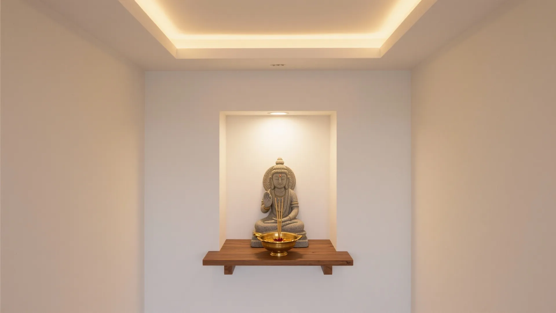 Buddha statue on a wood shelf in a wall niche with warm hidden ceiling light effect