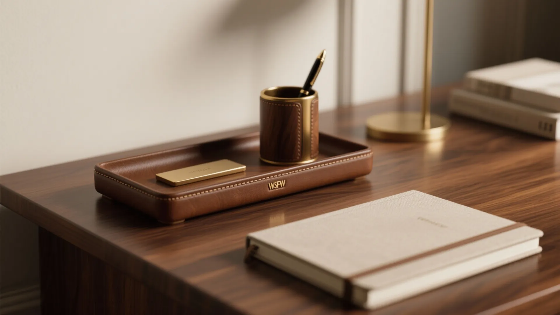 Brown leather desk tray with pen holder notebook and gold accessories on a wooden desk