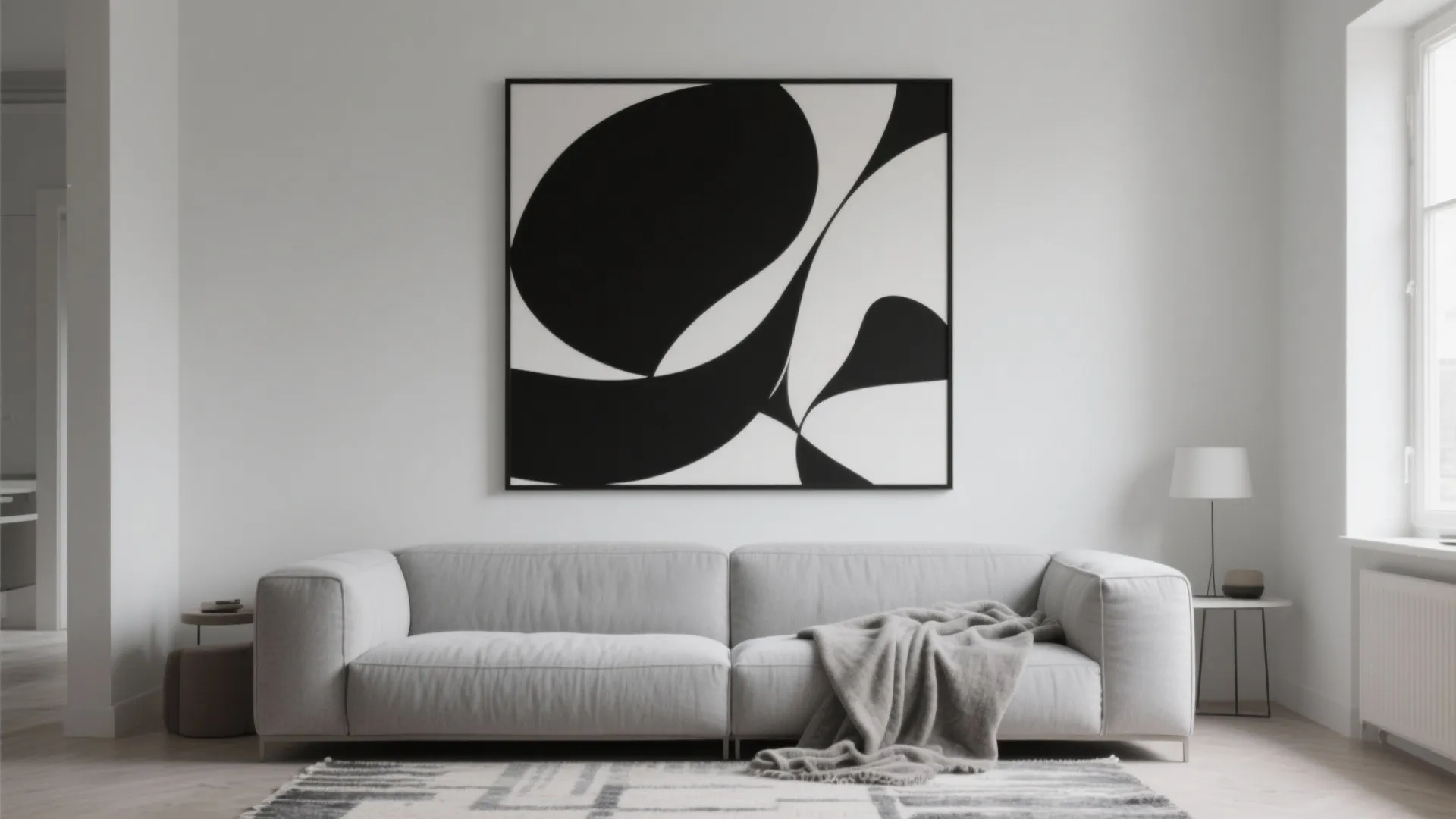 Black and white minimalist abstract canvas above light grey sofa in a Scandinavian living room