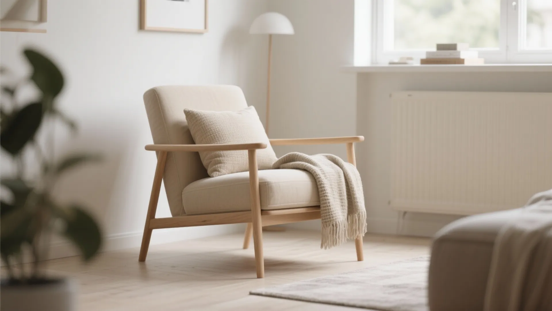 Beige chair with a soft pillow and blanket in a sunlit room with white walls