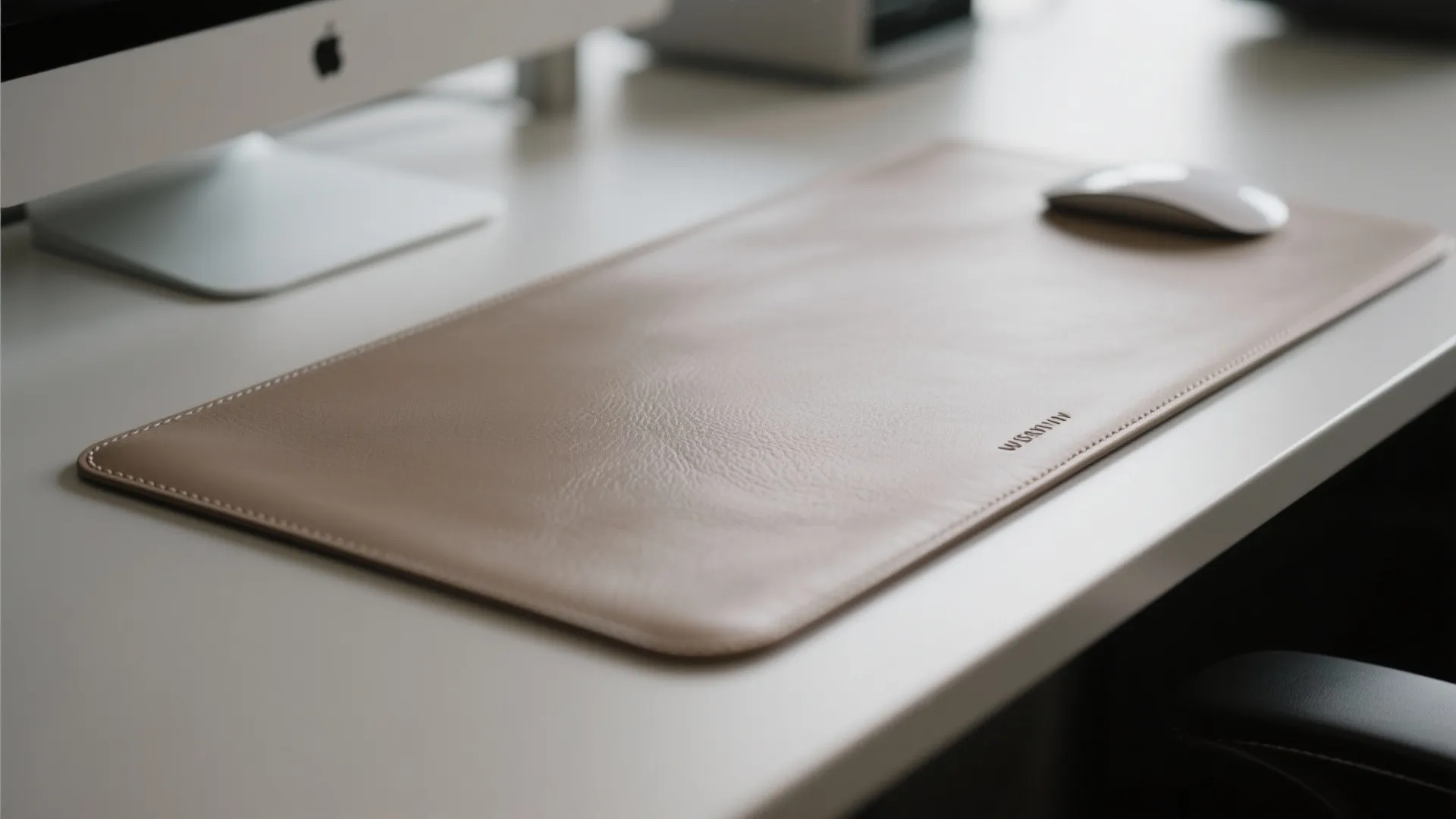 Beige leather desk mat with a computer mouse on a white table in office setting
