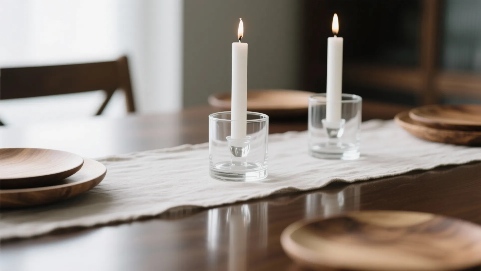 Glass candle holders with white candles and linen runner