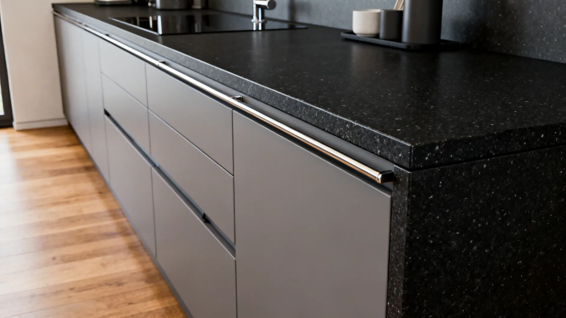 Narrow galley kitchen with honed black granite and integrated storage rails for a clean minimalist look.