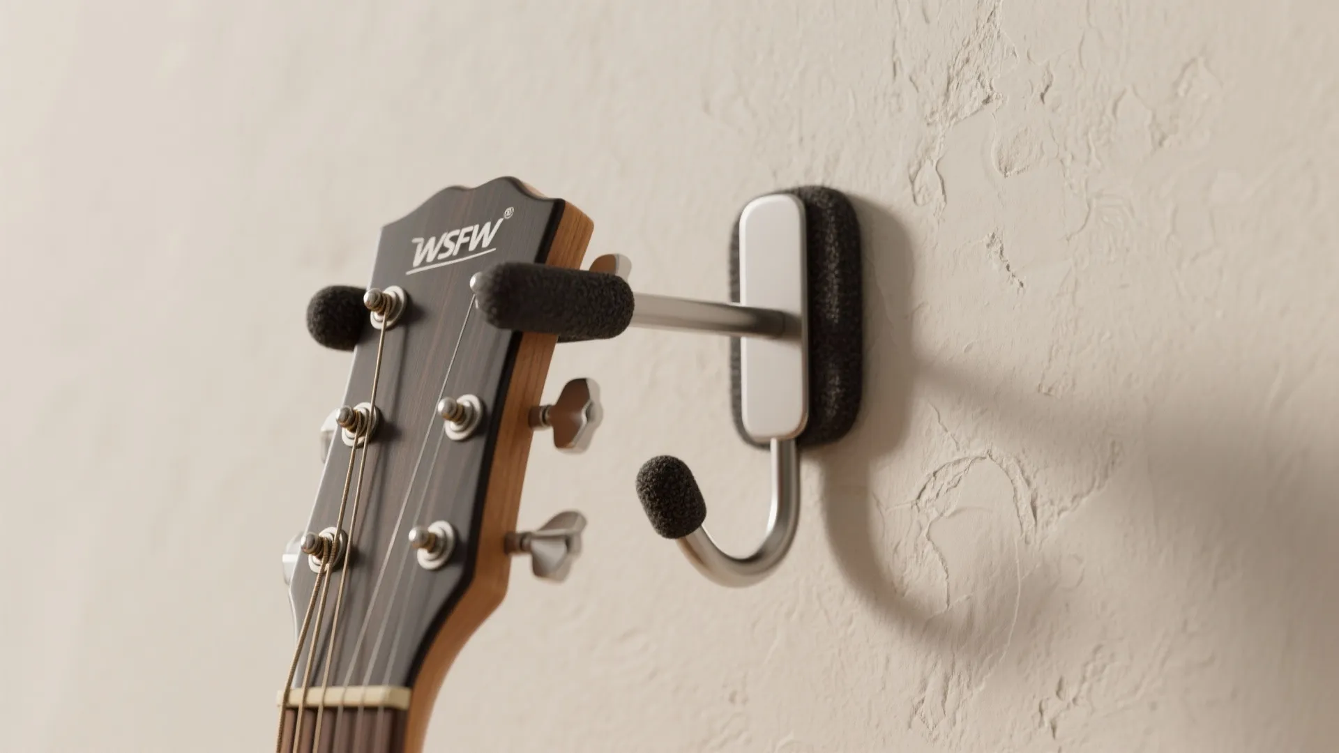 Close up of a metal wall hook holding a guitar head against a textured wall
