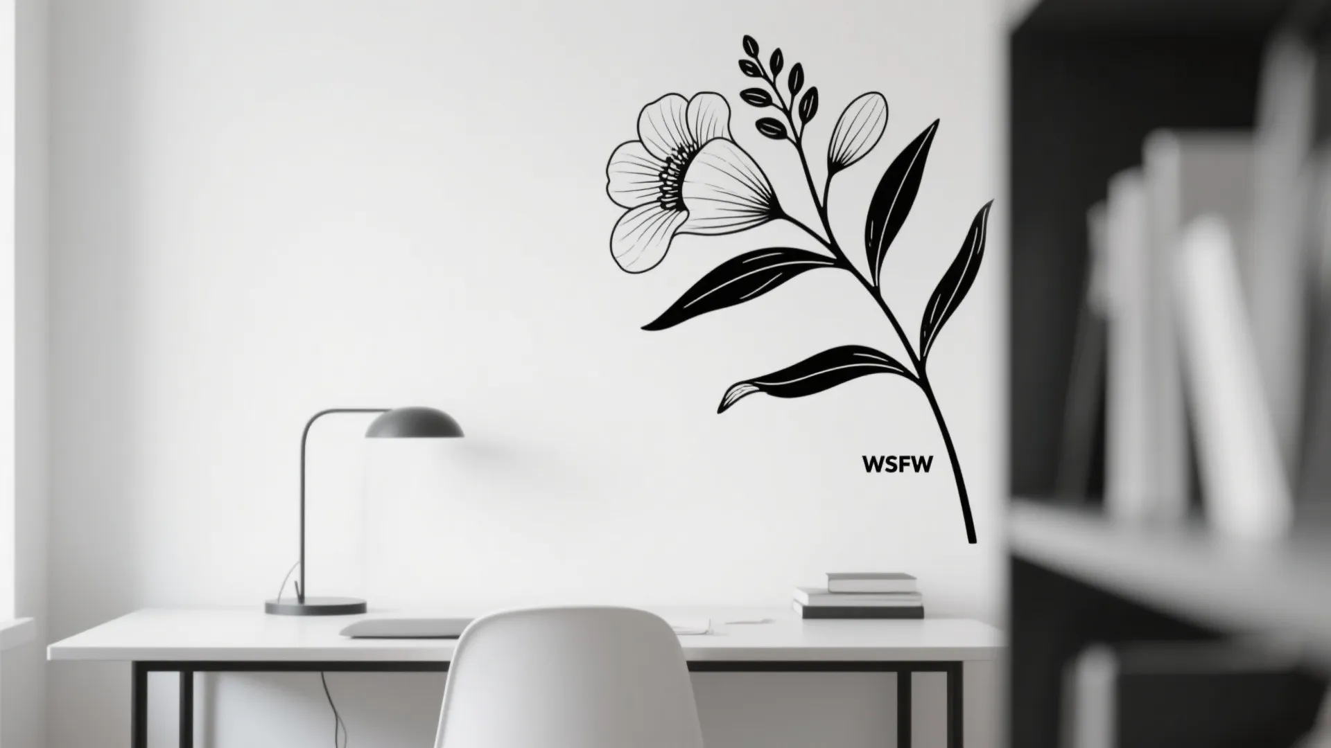 Black floral line art wall decal above a white desk with a simple black lamp