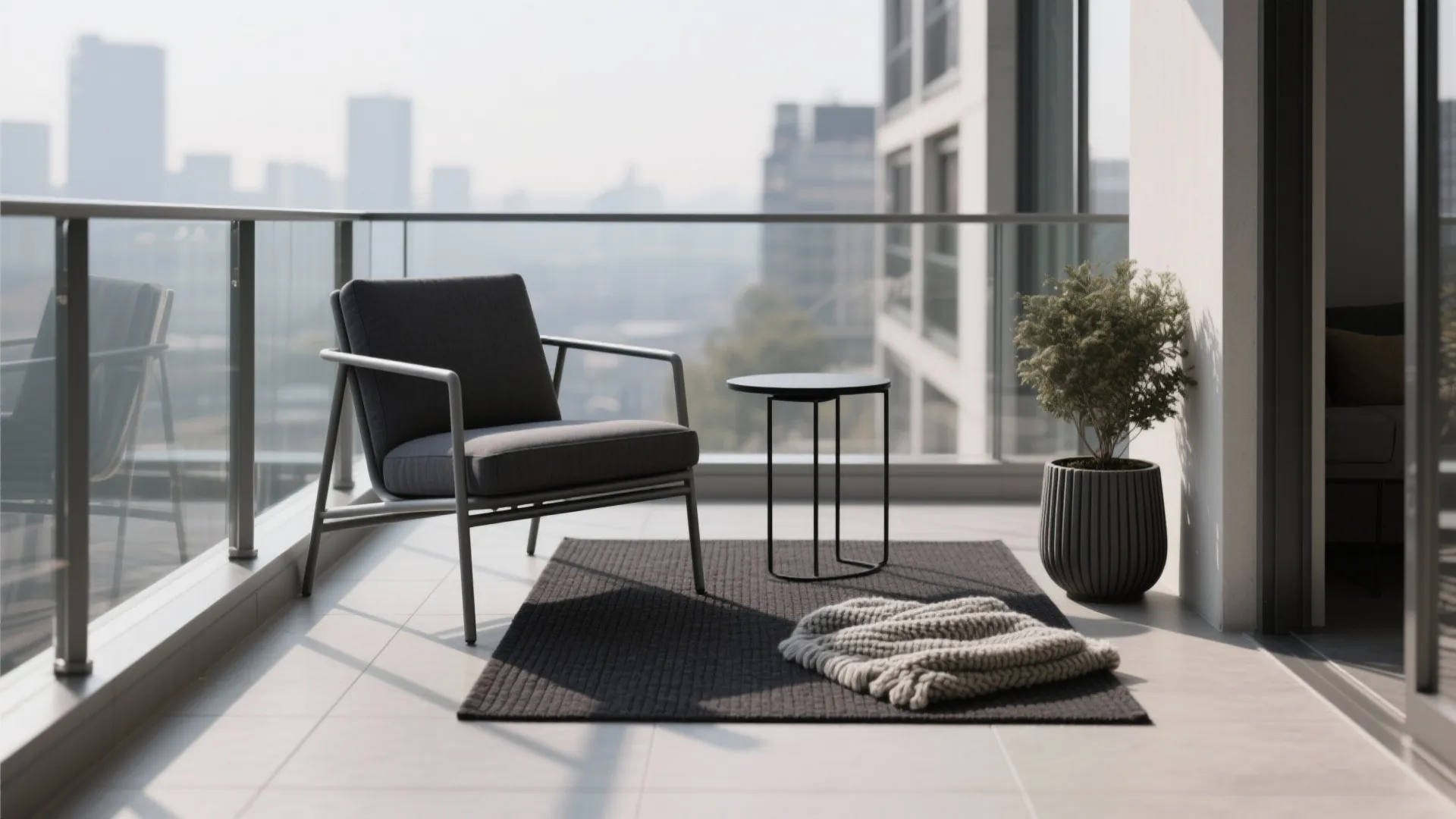Modern grey chair on a balcony with a small black table and a potted plant