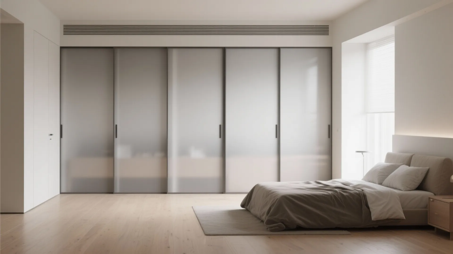 Minimalist bedroom featuring large grey sliding cabinet doors and a simple bed on wood flooring