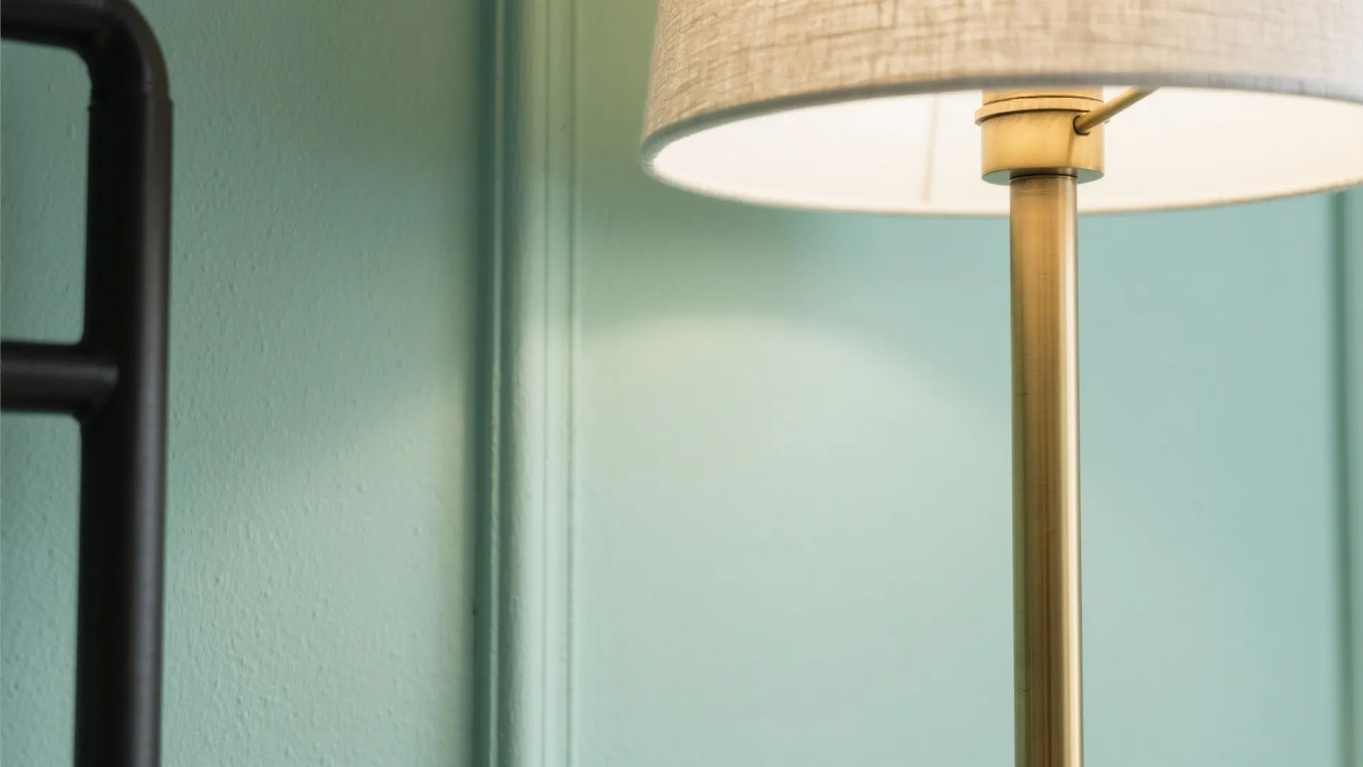 Close up of a brass floor light fixture against a light green wall panel background