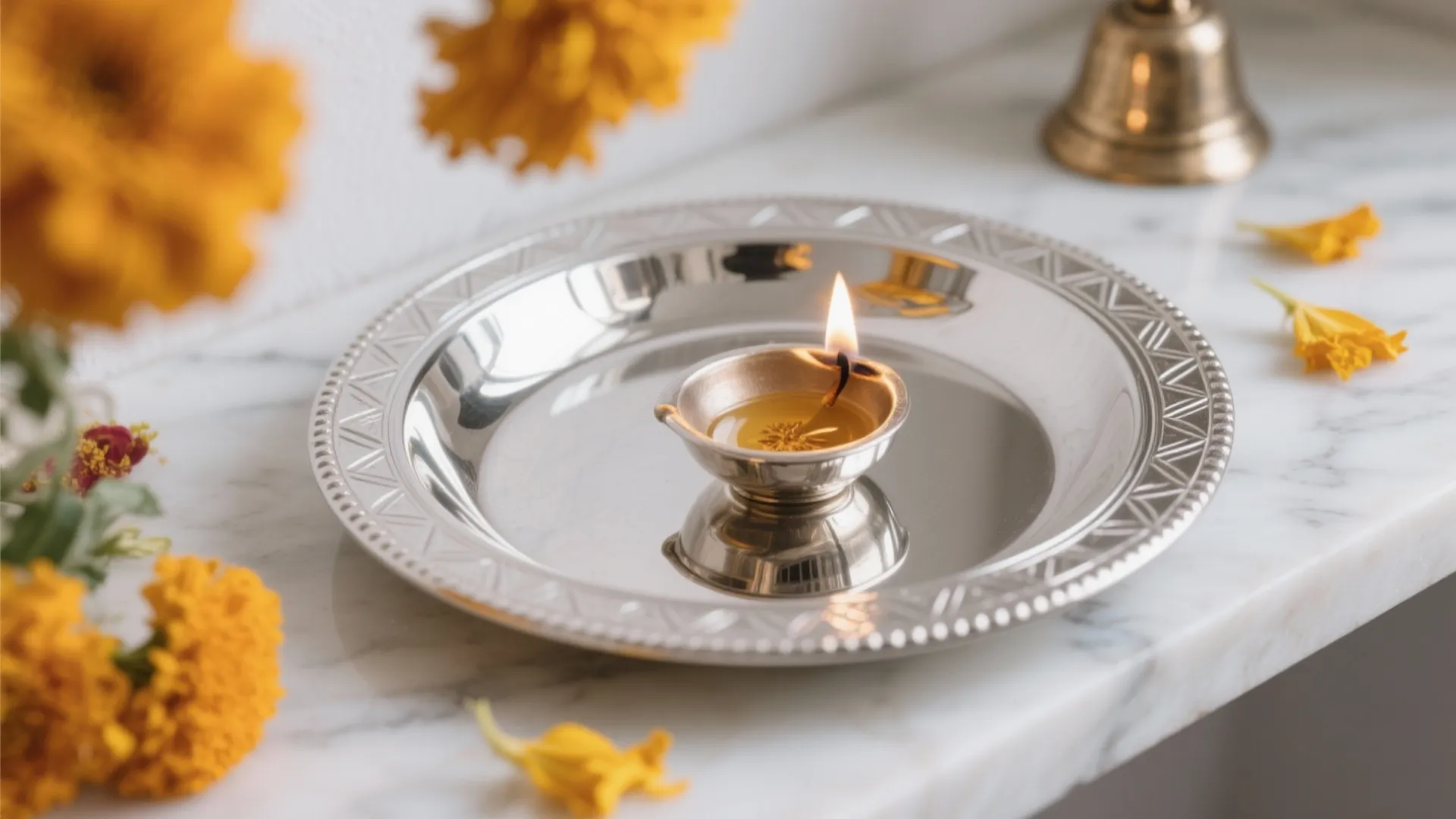 Close up of a lit small oil lamp on a shiny silver plate with flowers