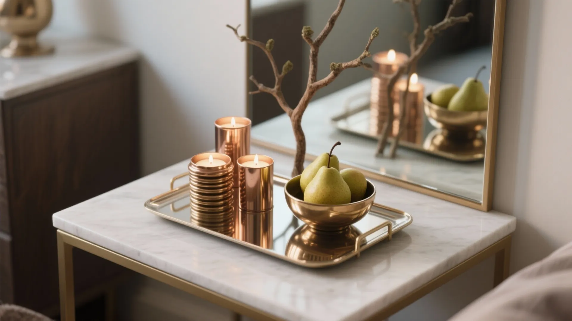 Mirrored tray with brass votives, a bowl of pears, and an artful branch creating a luxe small-table centerpiece.