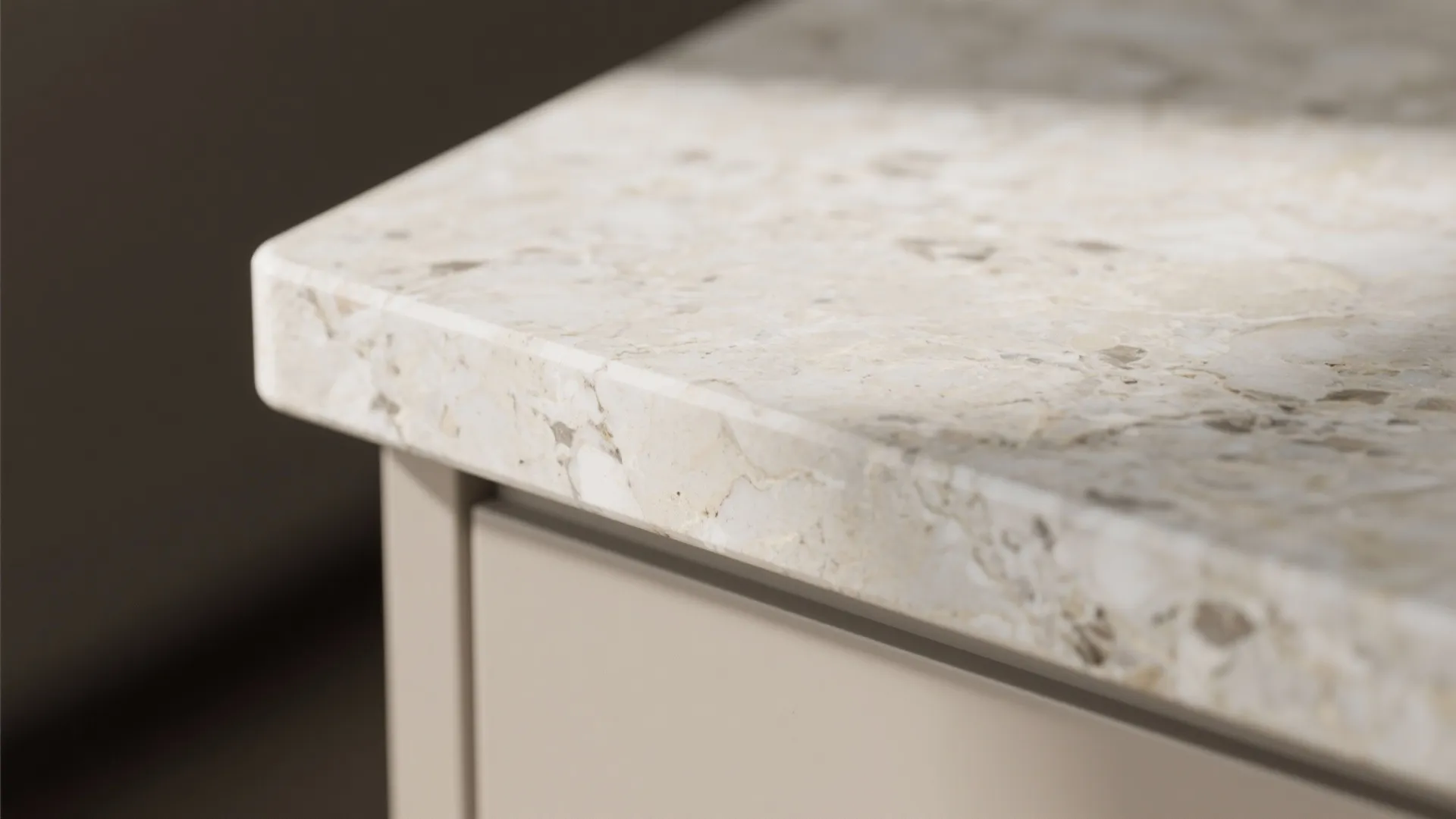 Close-up of a light stone countertop edge on top of a modern grey kitchen cabinet