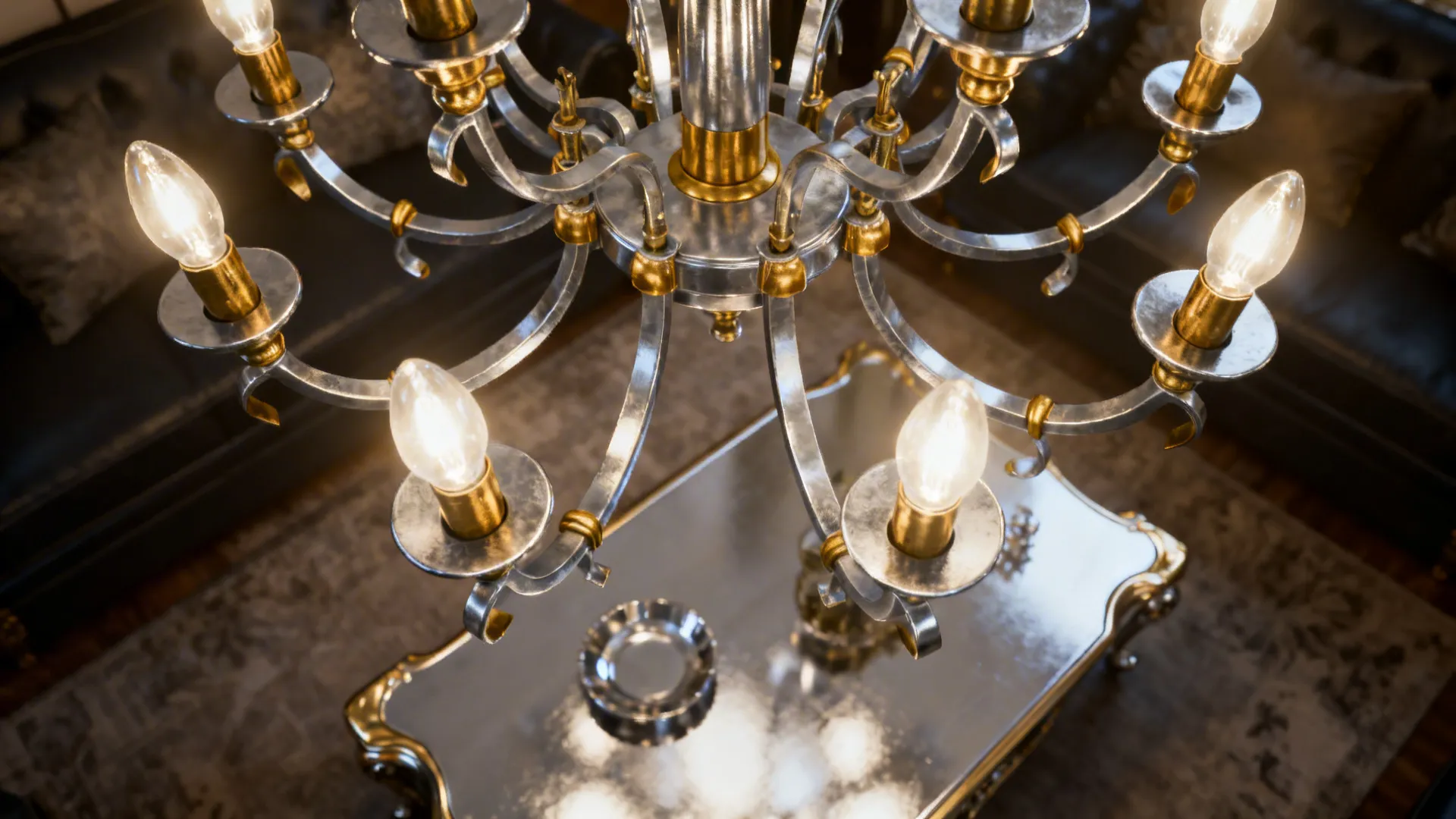 Large silver and gold ceiling light with many bulbs hanging above a shiny coffee table