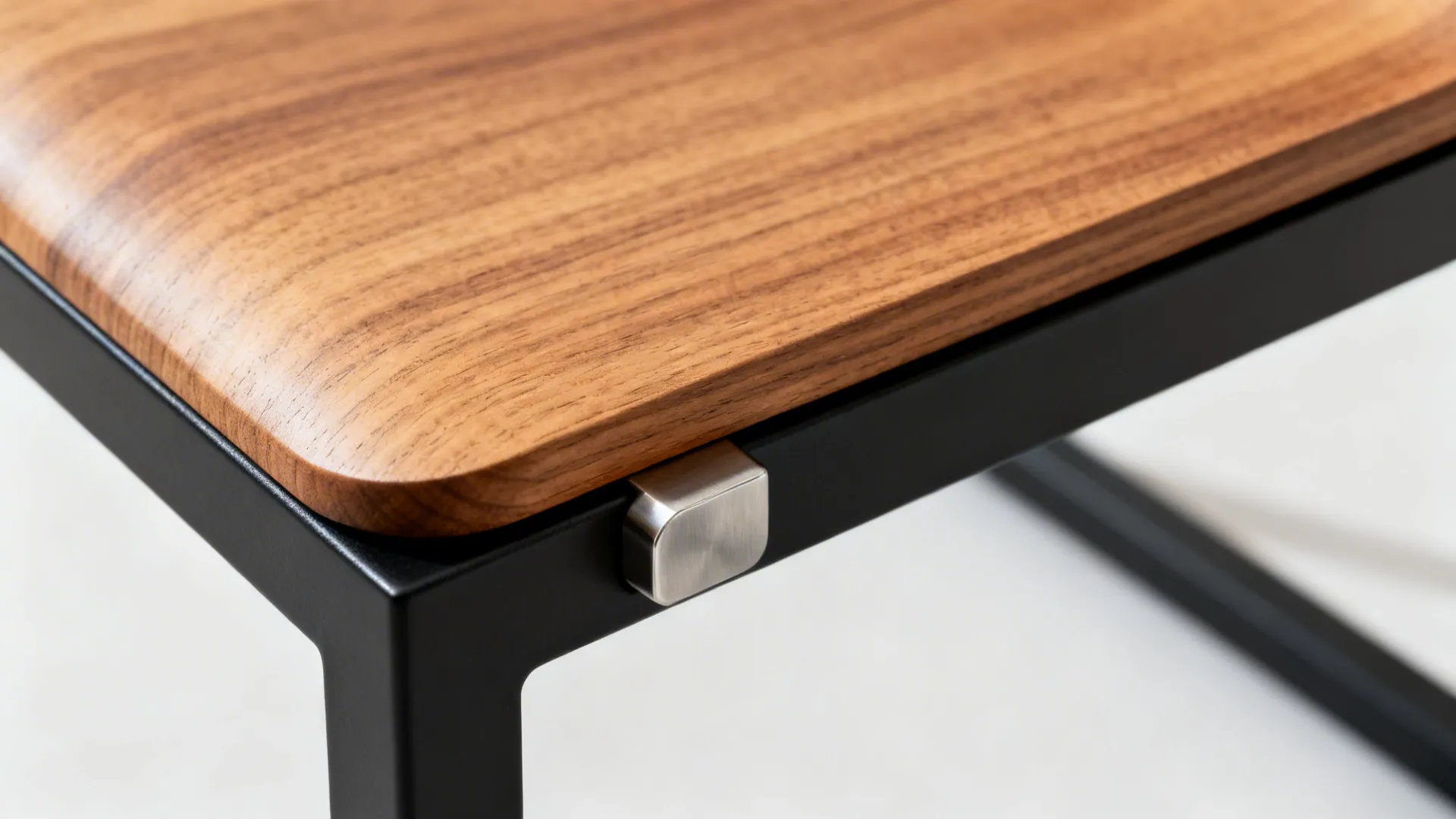 Close-up of an oak stool seat meeting a matte black powder-coated steel frame.