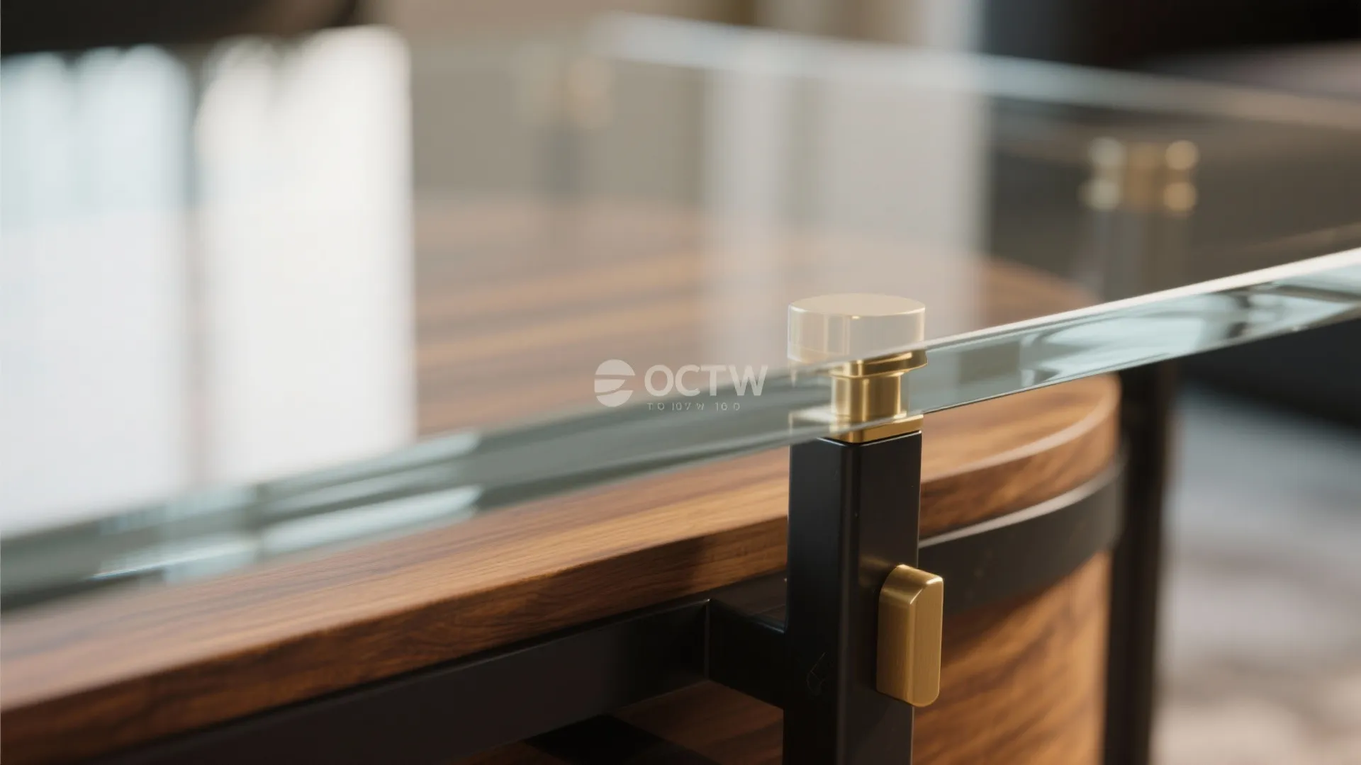 Close up of glass table top joined to dark wood base with a gold metal part