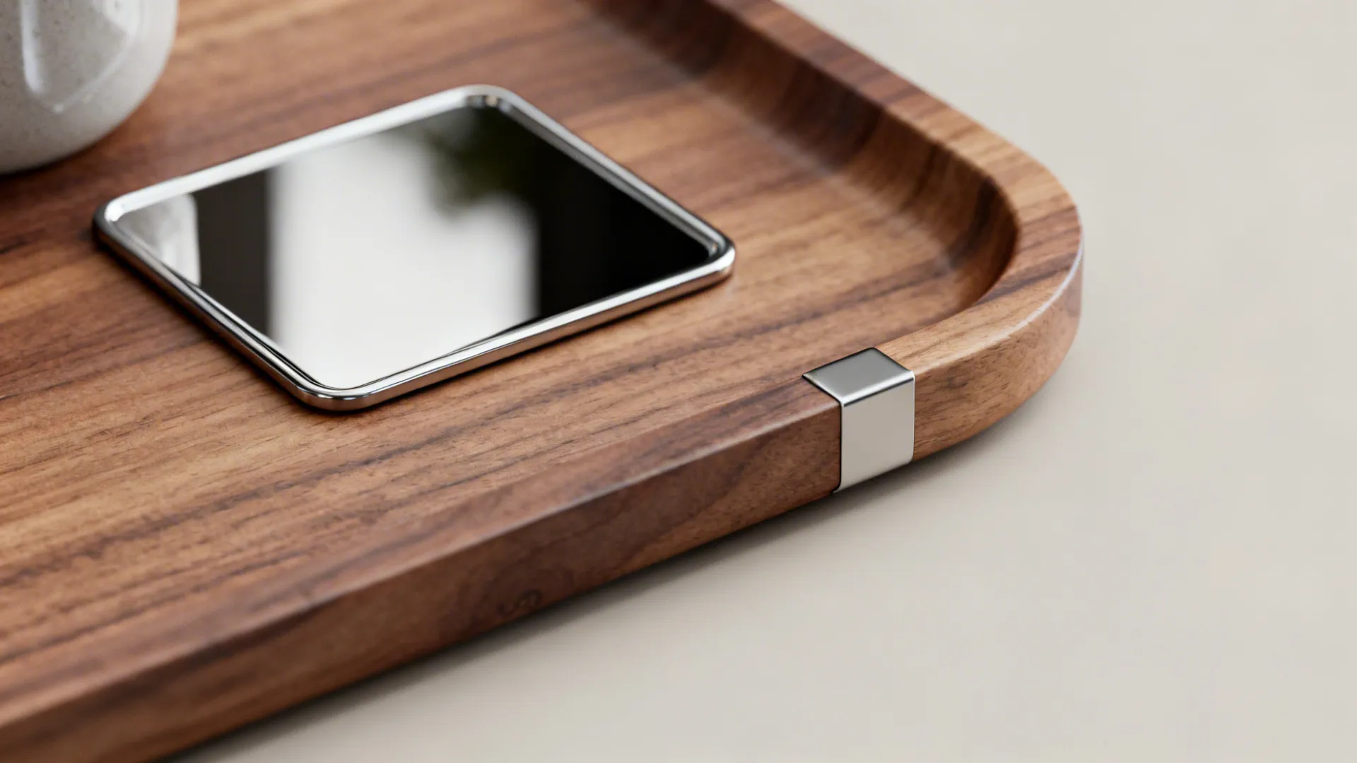 Close-up of mixed tray materials: wood base with metal accent and mirrored coaster.