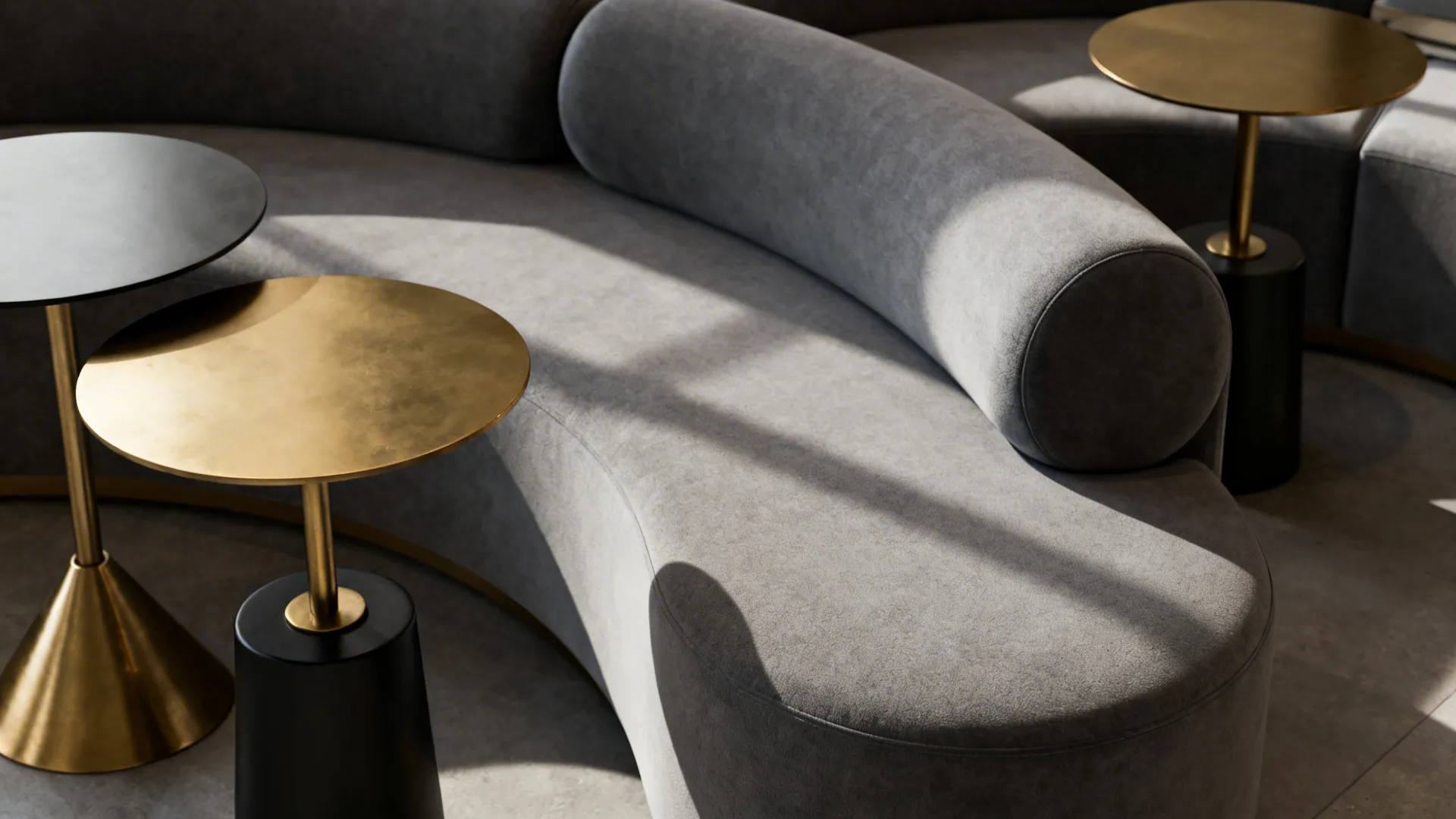 Curved gray sectional with brass and matte black side tables in close detail.