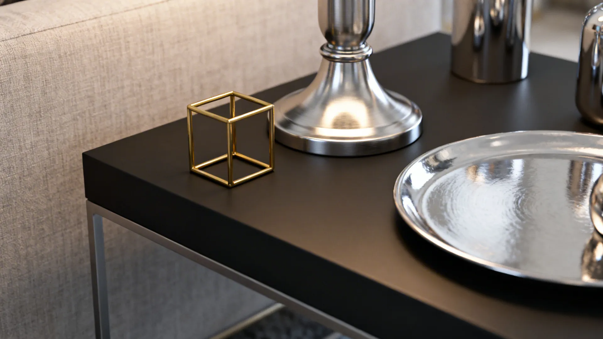 Close-up of brushed nickel lamp, brass frame and matte black coffee table edge.