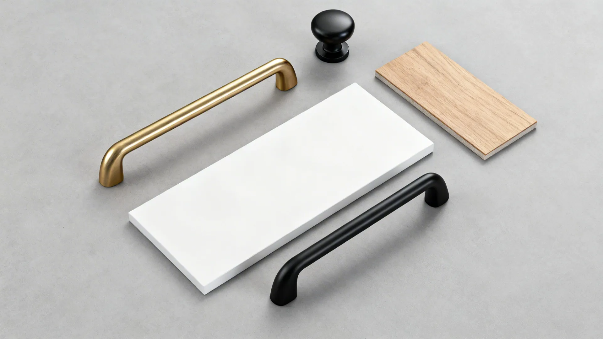 Flat lay of brushed brass pull and matte black knob with wood and white cabinet swatches.