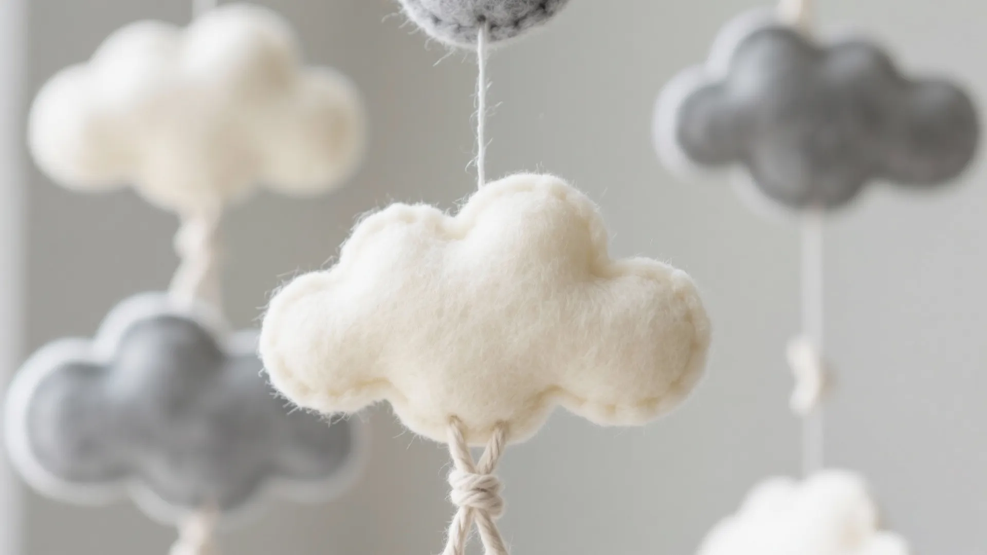 White and grey soft felt cloud decorations hanging on strings for a nursery room ceiling