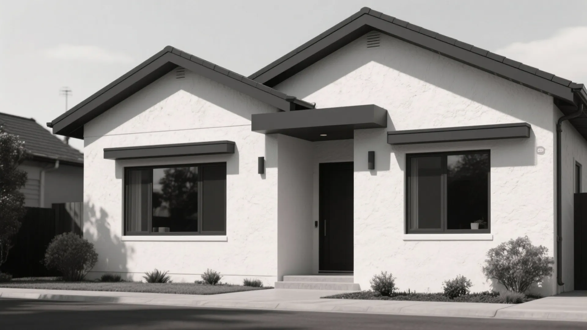 Modern black and white house with dark gabled roof large windows front door and green bushes