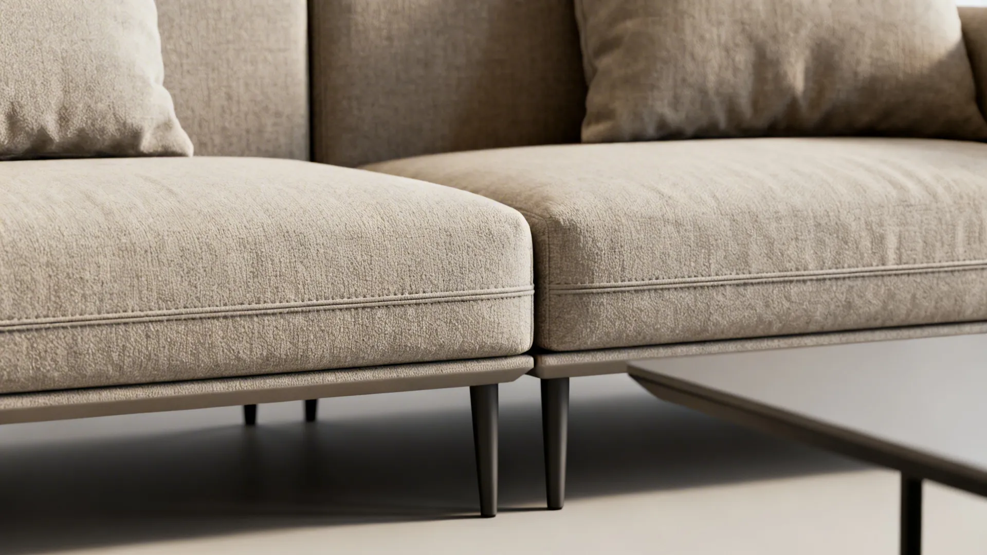 Close up of beige fabric sofa cushions with dark legs and a grey coffee table