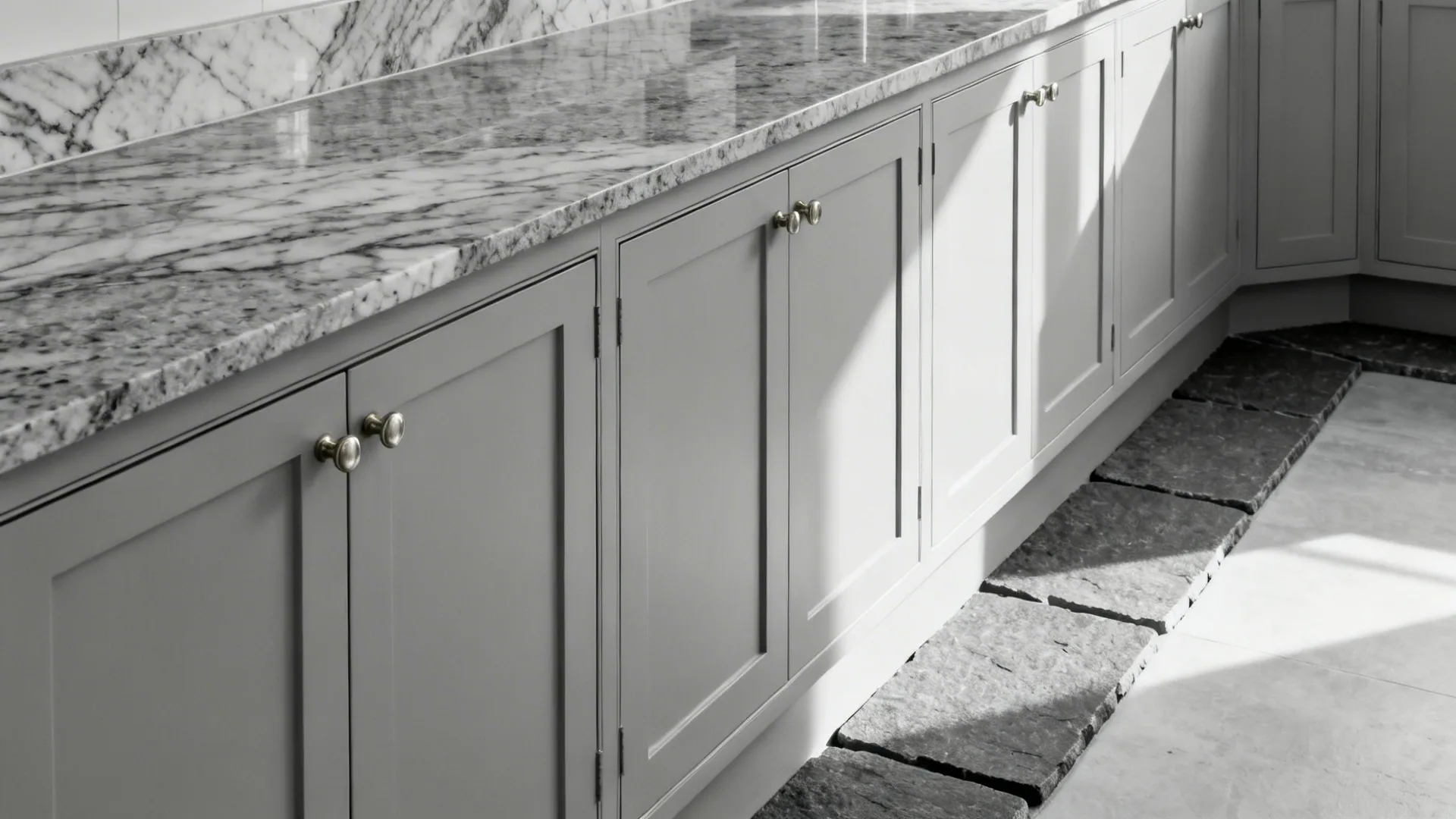 Monochrome gray kitchen with pale cabinets, mid-gray granite, and deep gray thresholds.