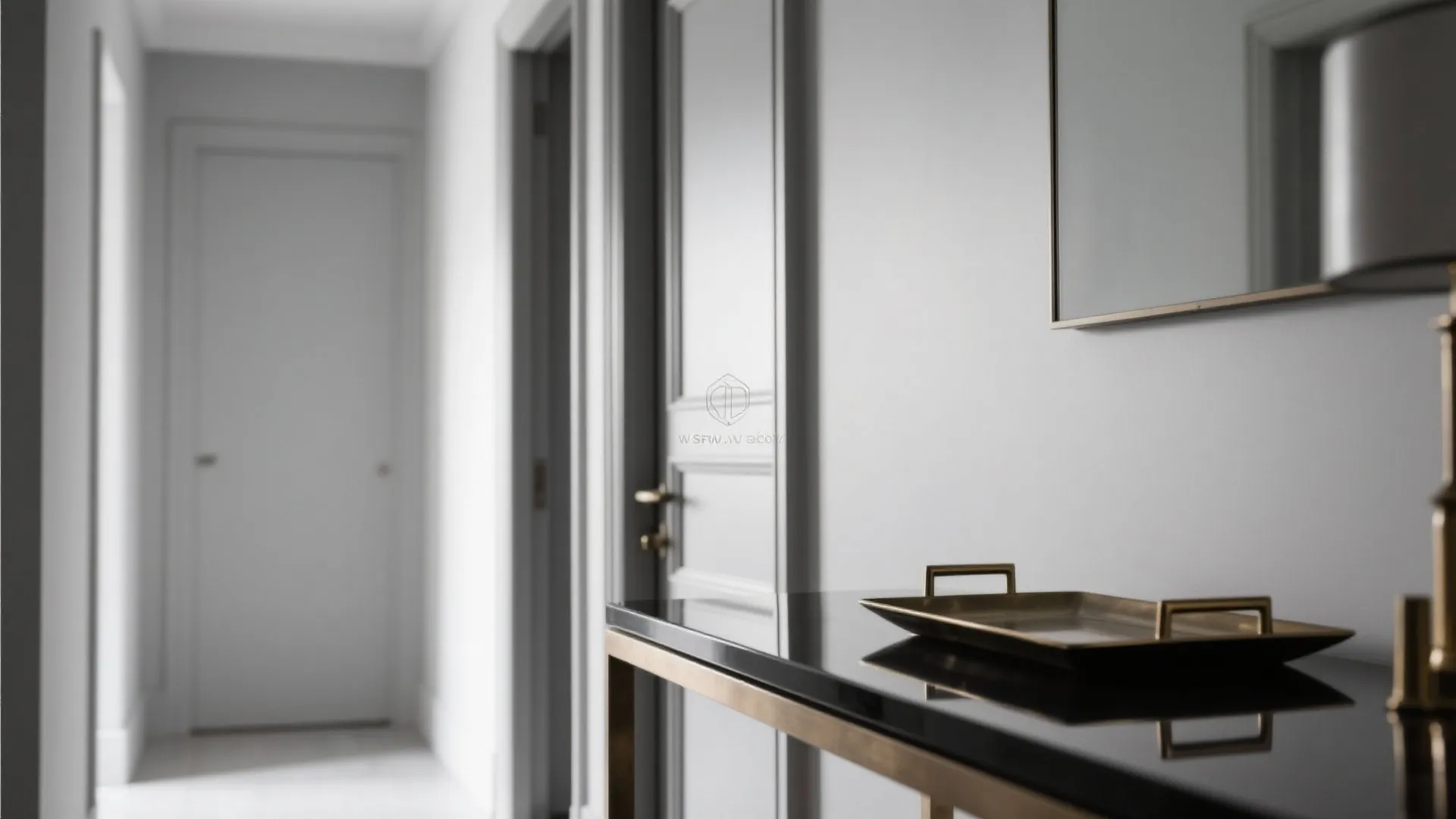 Modern hallway with grey walls a black console table gold tray and several white doors