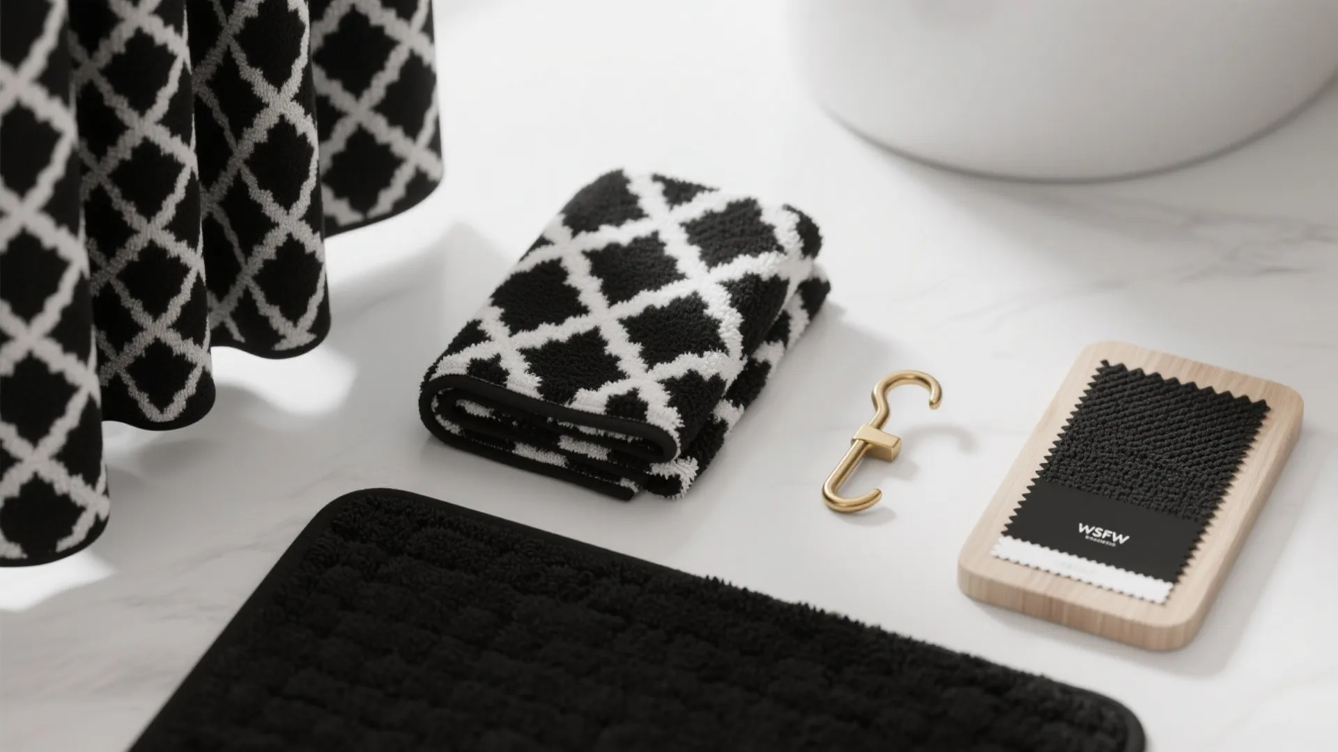 Flatlay of black-and-white towels, bath mat and curtain fabric swatches with brass hook sample