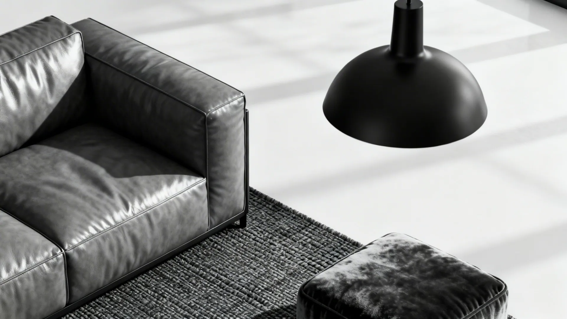 Close-up of grey leather couch with matte black lighting and charcoal rug in monochrome room.