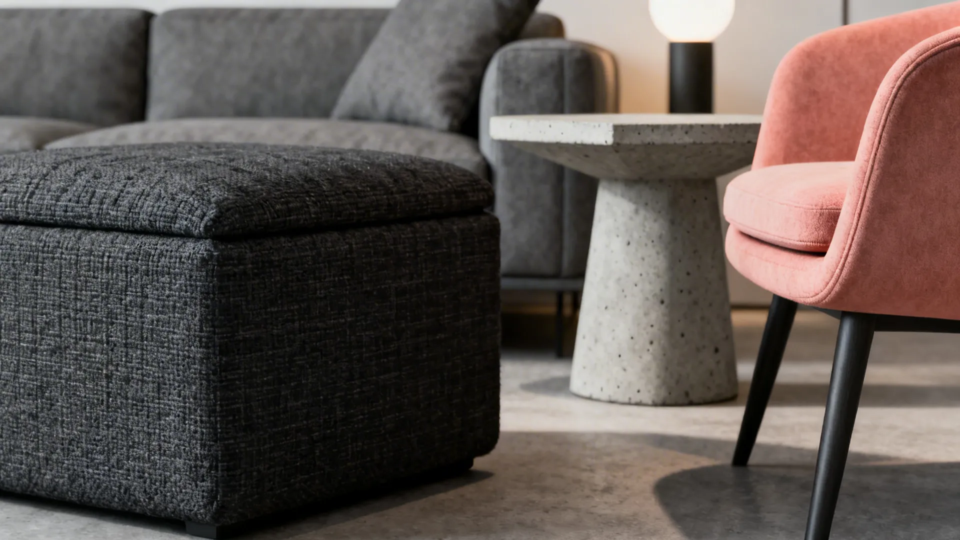 Monochrome grey vignette with a coral-pink accent chair and detailed fabric and concrete textures.