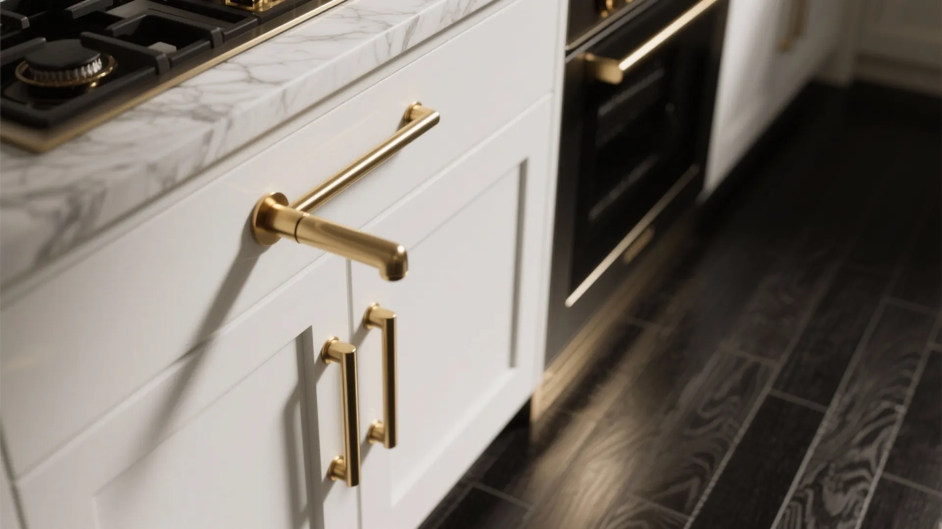 Close up of white kitchen cabinets with gold handles and a marble countertop near stove