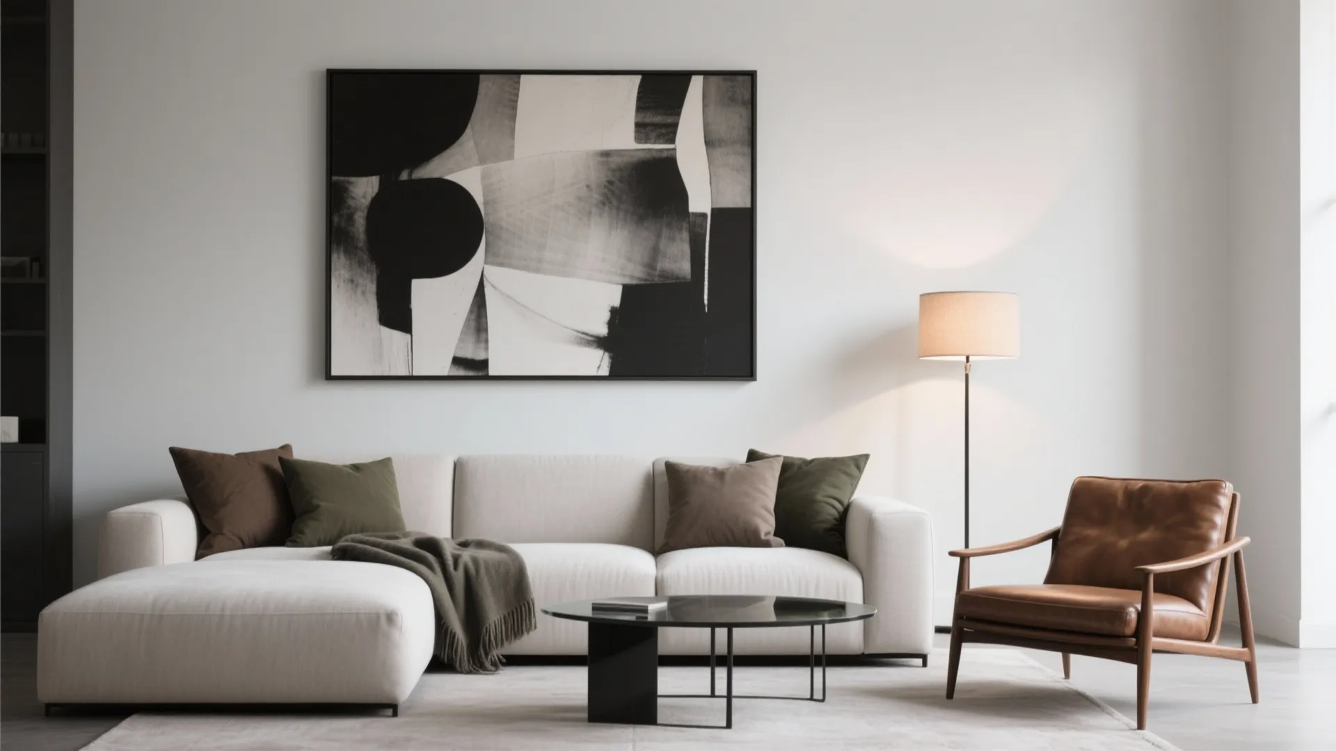 Minimalist living room featuring white sofa leather armchair black abstract wall art and floor lamp