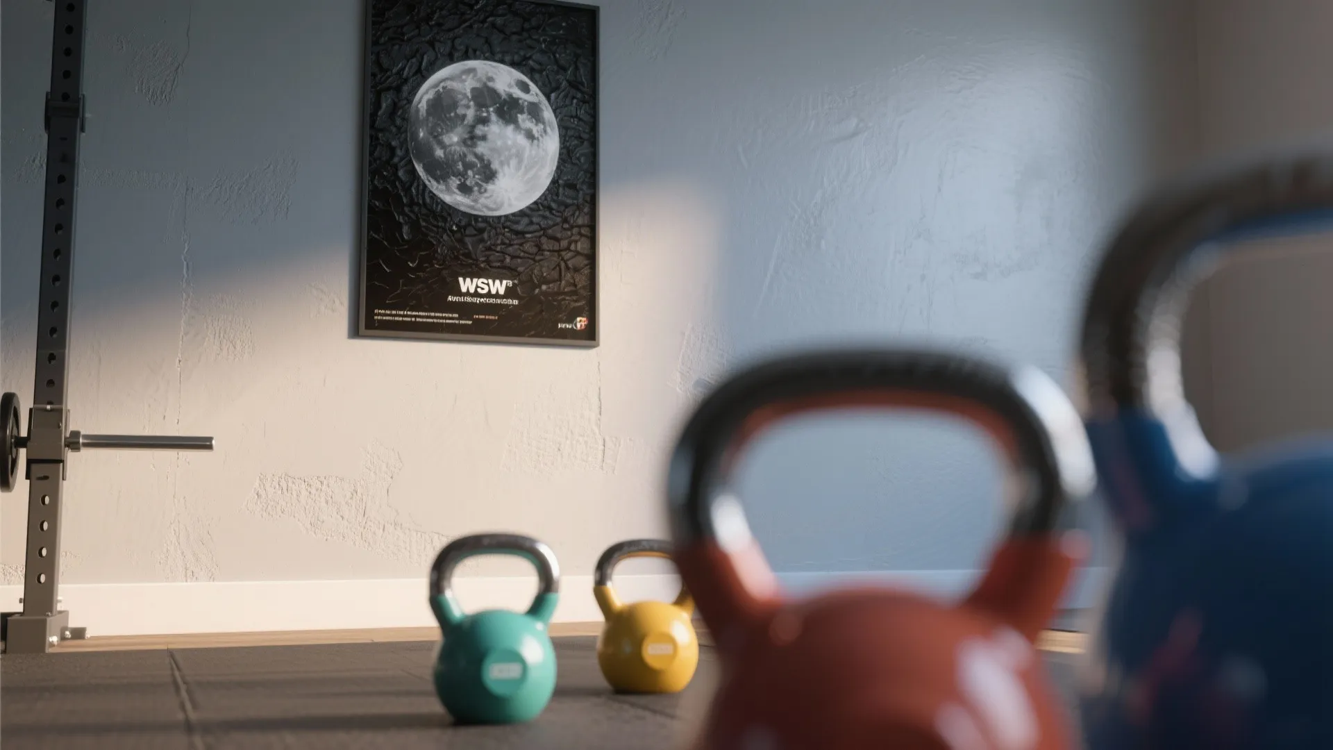 Colorful gym kettlebells on the floor with a moon poster hanging on the light wall