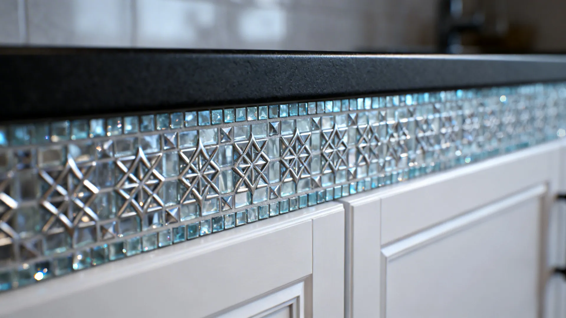 Blue glass mosaic tile border on white kitchen cabinets underneath a dark stone kitchen countertop