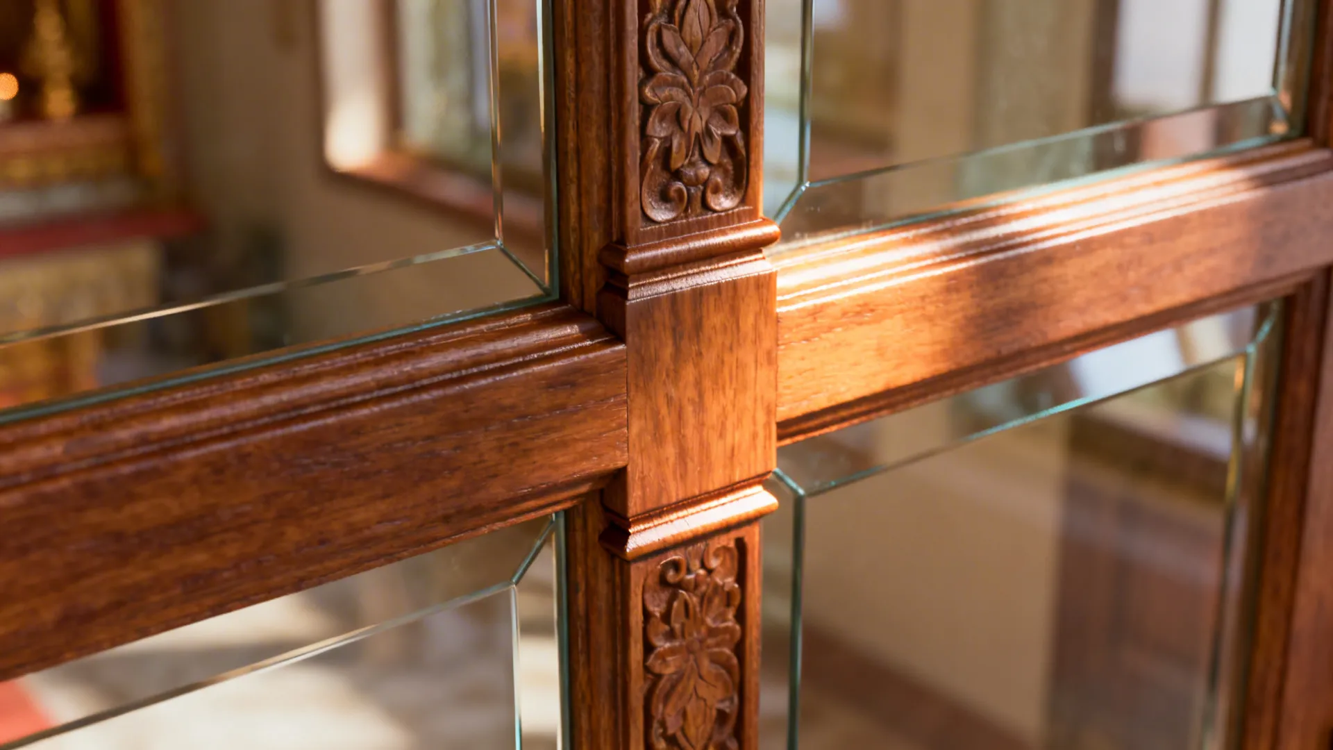 Close-up of a carved wooden mullion and clear glass joint on a pooja door.