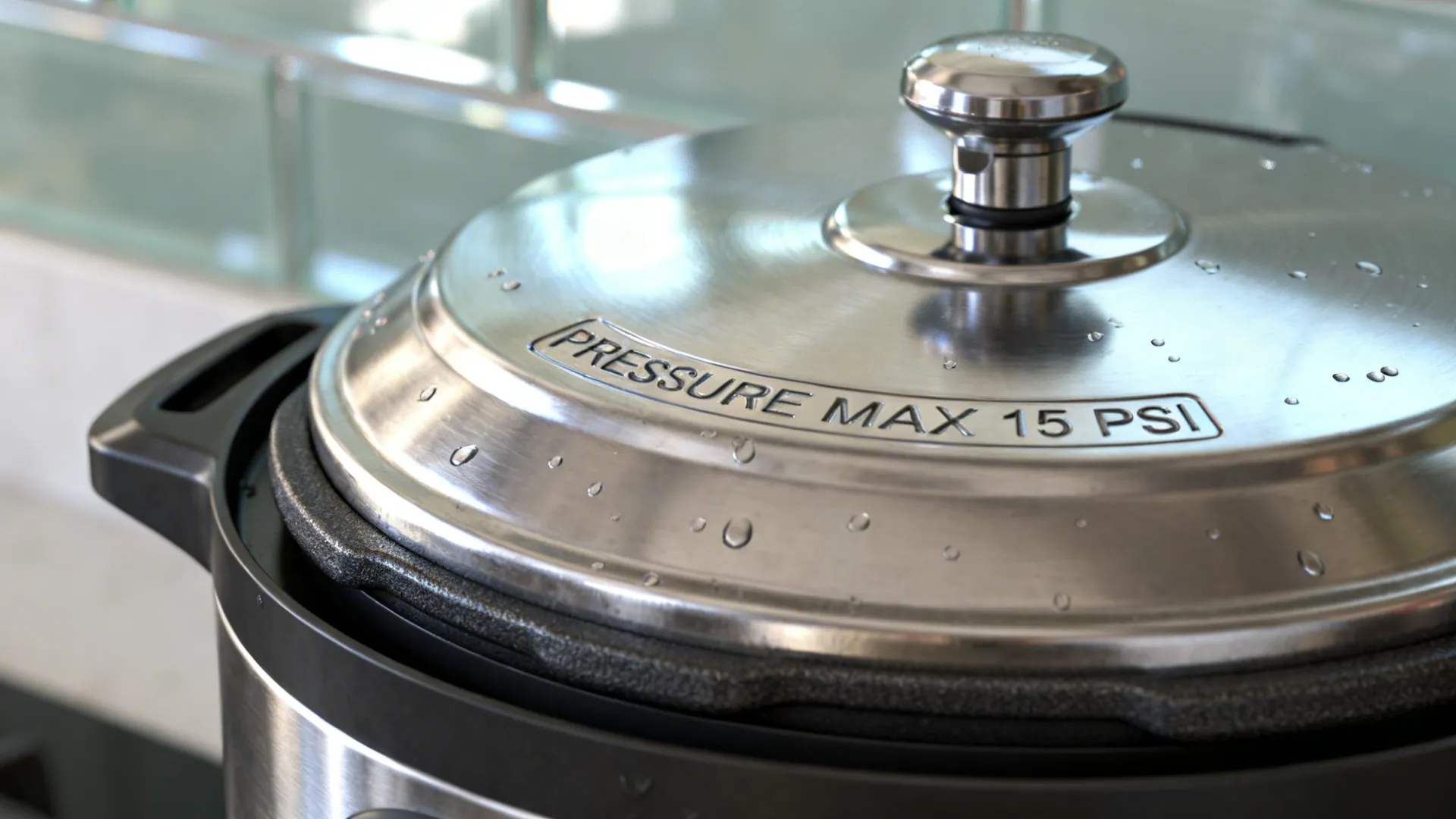 Macro view of multi‑cooker steam valve and brushed stainless lid in soft light.