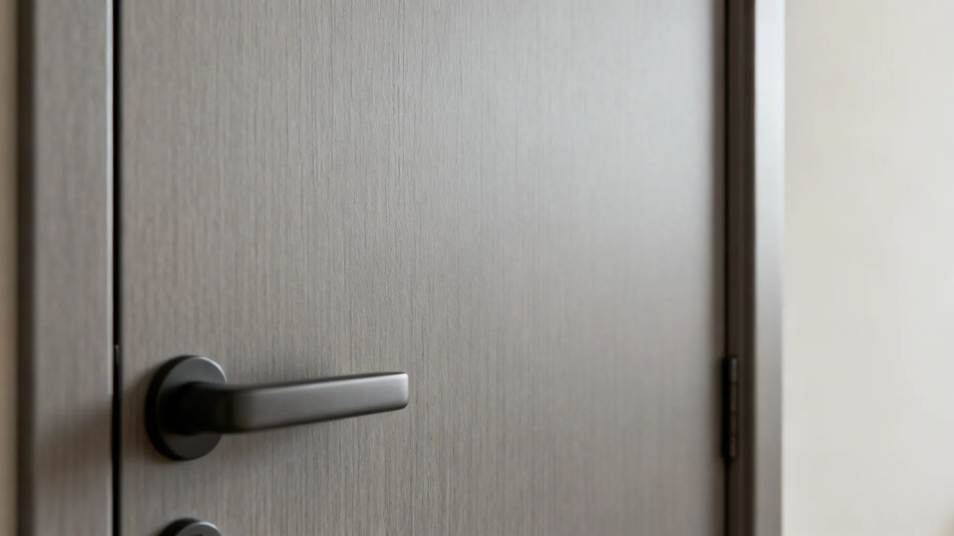 Close up of a grey room door with a black handle and smooth matte finish texture