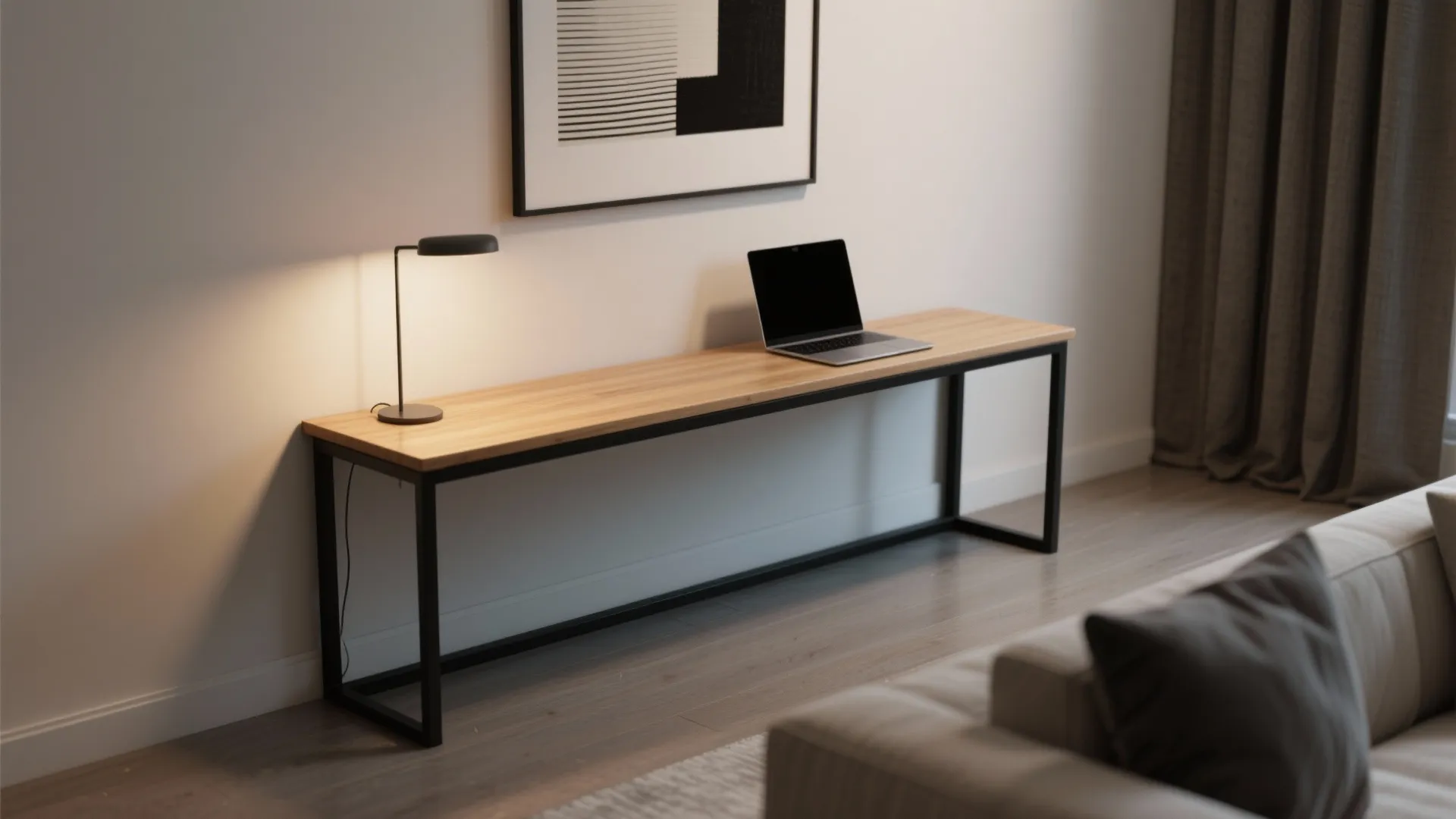 Minimalist wooden narrow desk with black legs featuring a laptop small lamp and wall art
