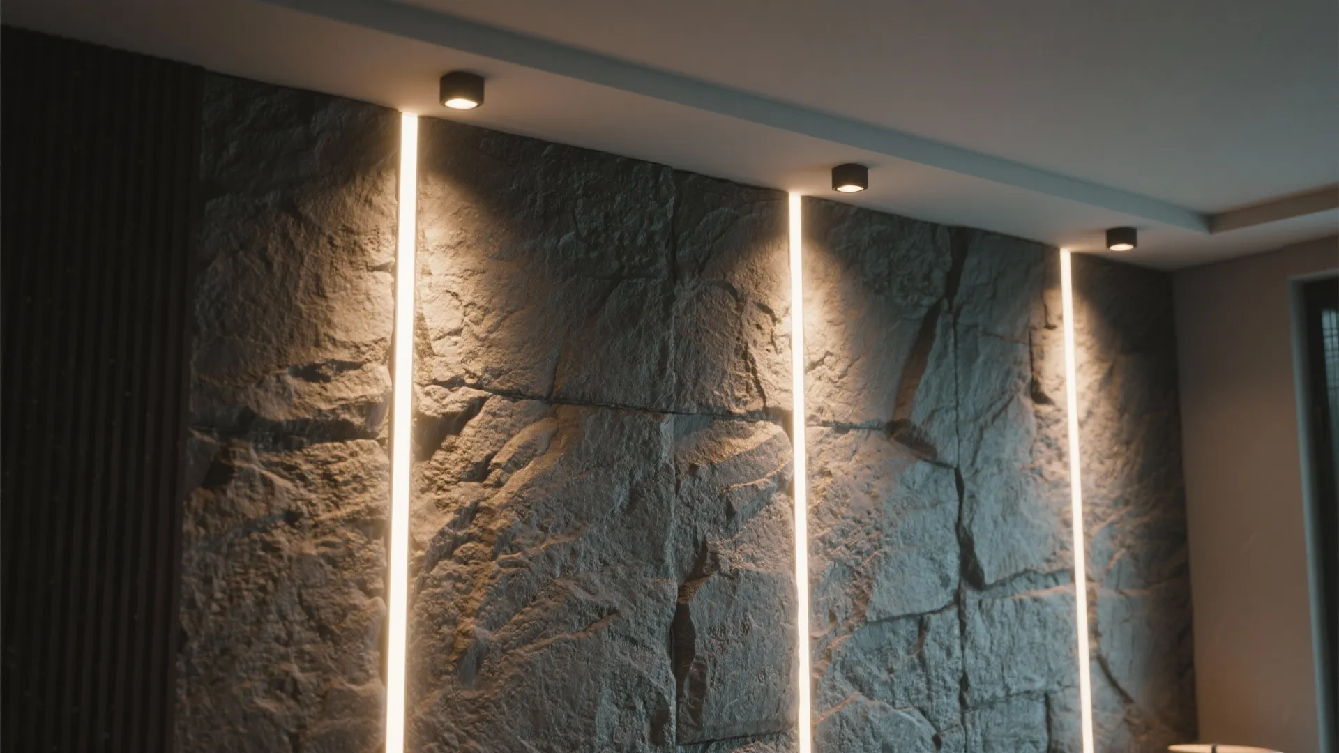 Textured accent wall lit by narrow-beam recessed spotlights creating dramatic highlights.