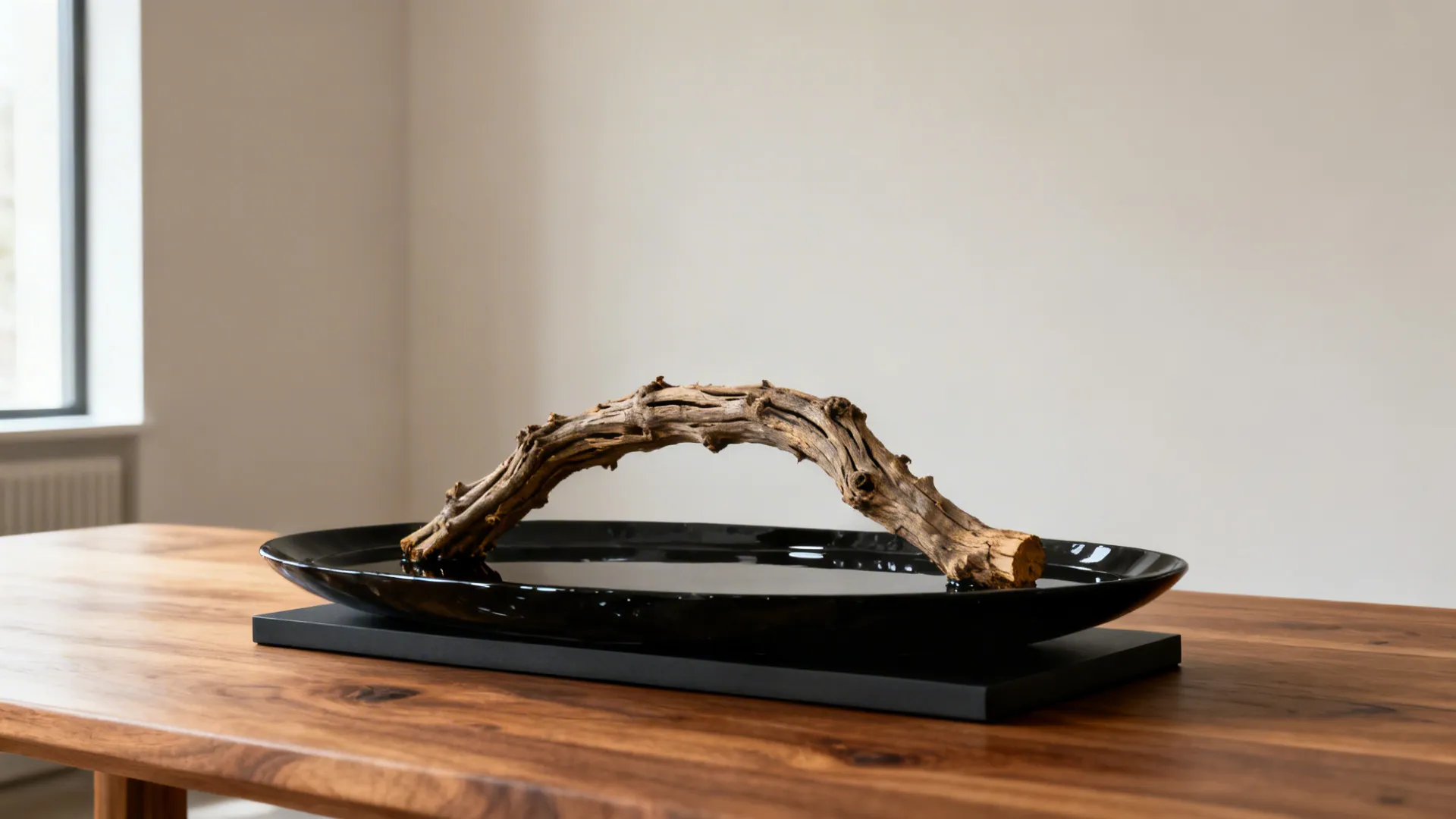 Low natural grapevine or driftwood sculpture set in a sleek shallow dish on a dining table.