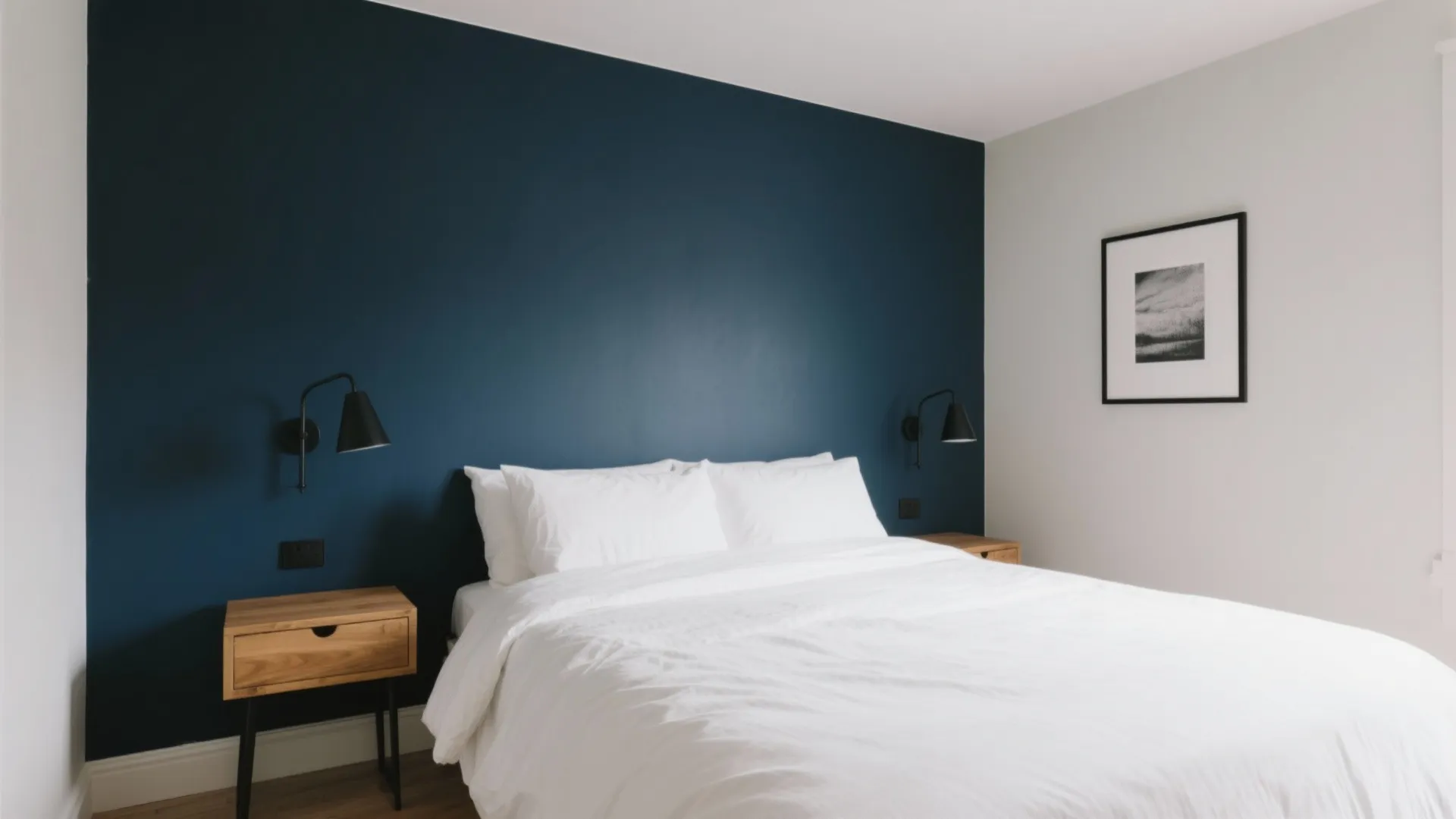Modern bedroom featuring a deep navy blue accent wall white bed wooden nightstands and lamps