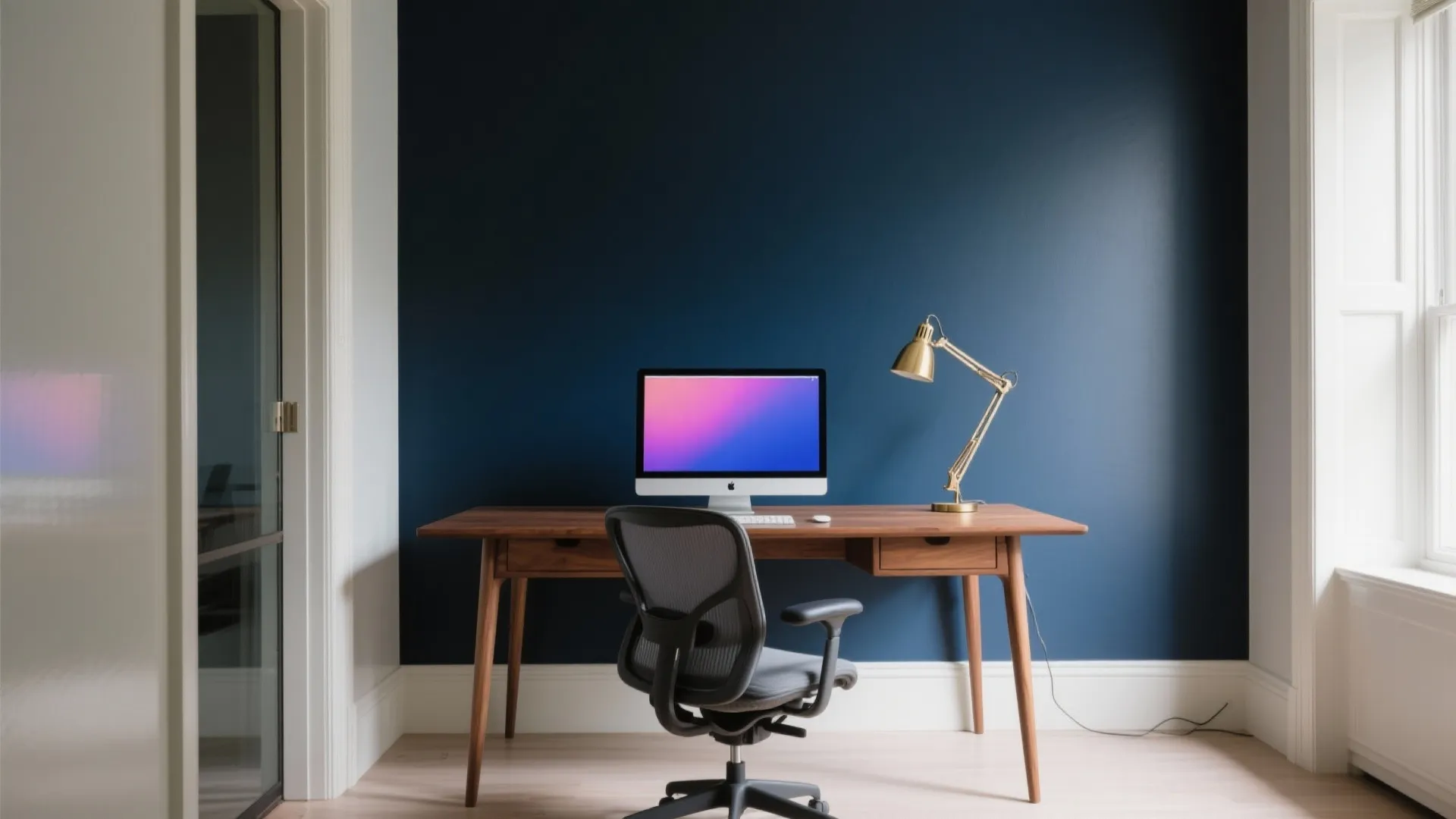 Modern home office with navy blue accent wall wooden desk black chair and gold desk lamp