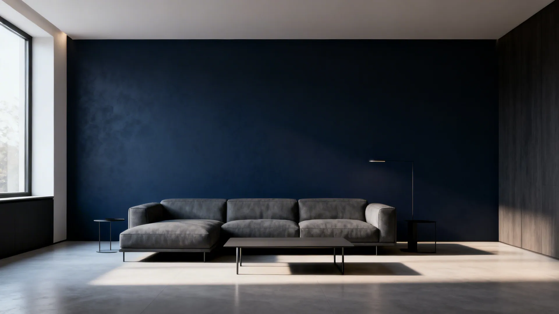 Minimal living room with a gray sectional placed before a deep navy accent wall.