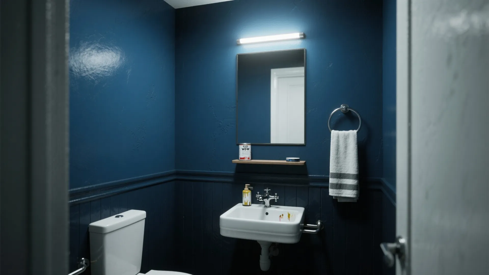 Small bathroom with dark blue walls featuring a white sink mirror and wall light fixture