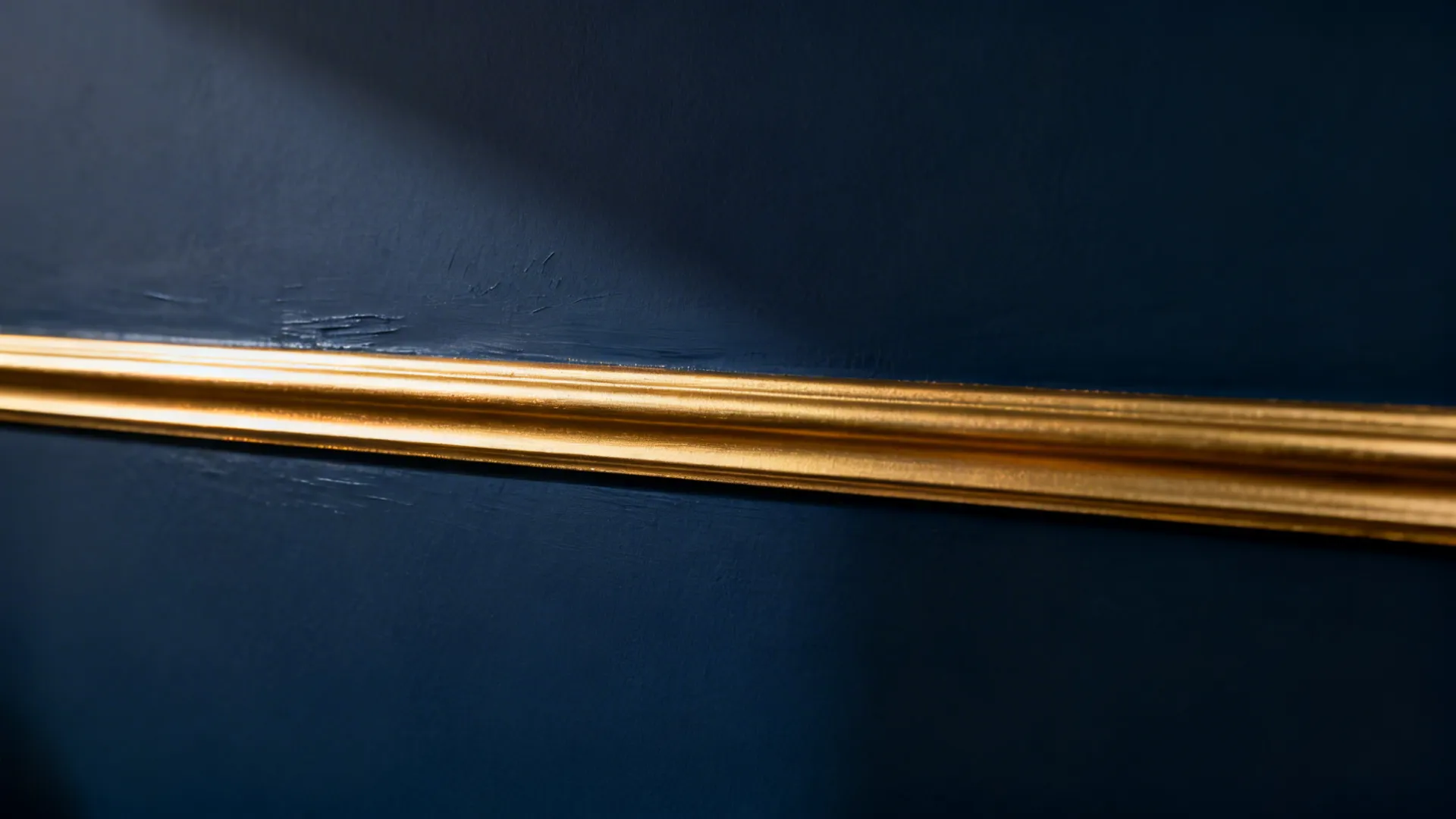 Close-up of a navy wall with a slim gold trim showing precise, clean paint edges.