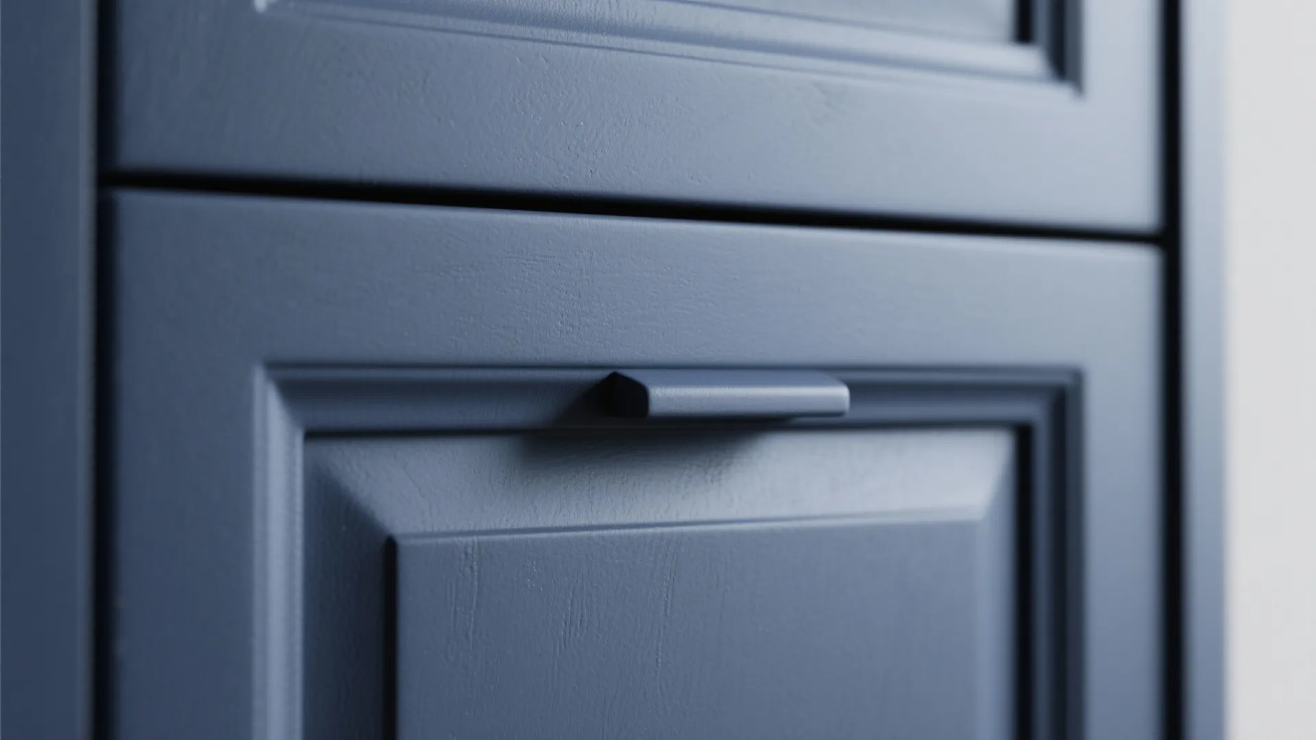 Close up of navy blue matte kitchen cabinet drawer with a matching small metal handle